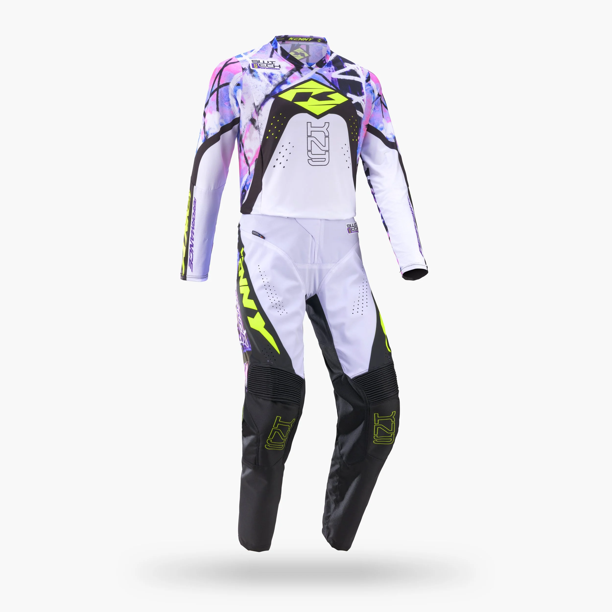 Le vêtement présenté dans l'image est un ensemble de motocross avec des couleurs vives, comprenant une veste et un pantalon, décoré de motifs géométriques et de logos. La veste arbore principalement des teintes de blanc, noir, violet, rose, avec des 