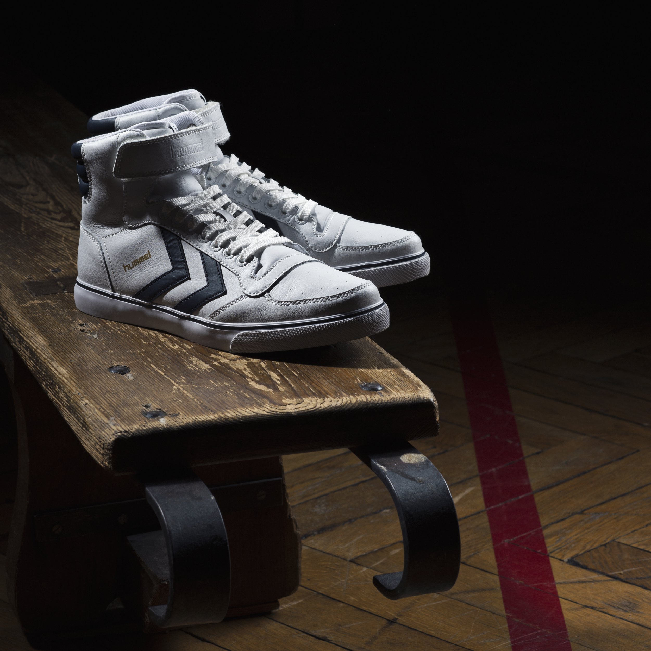 Chaussures de sport blanches sur une table en bois, avec un fond sombre.