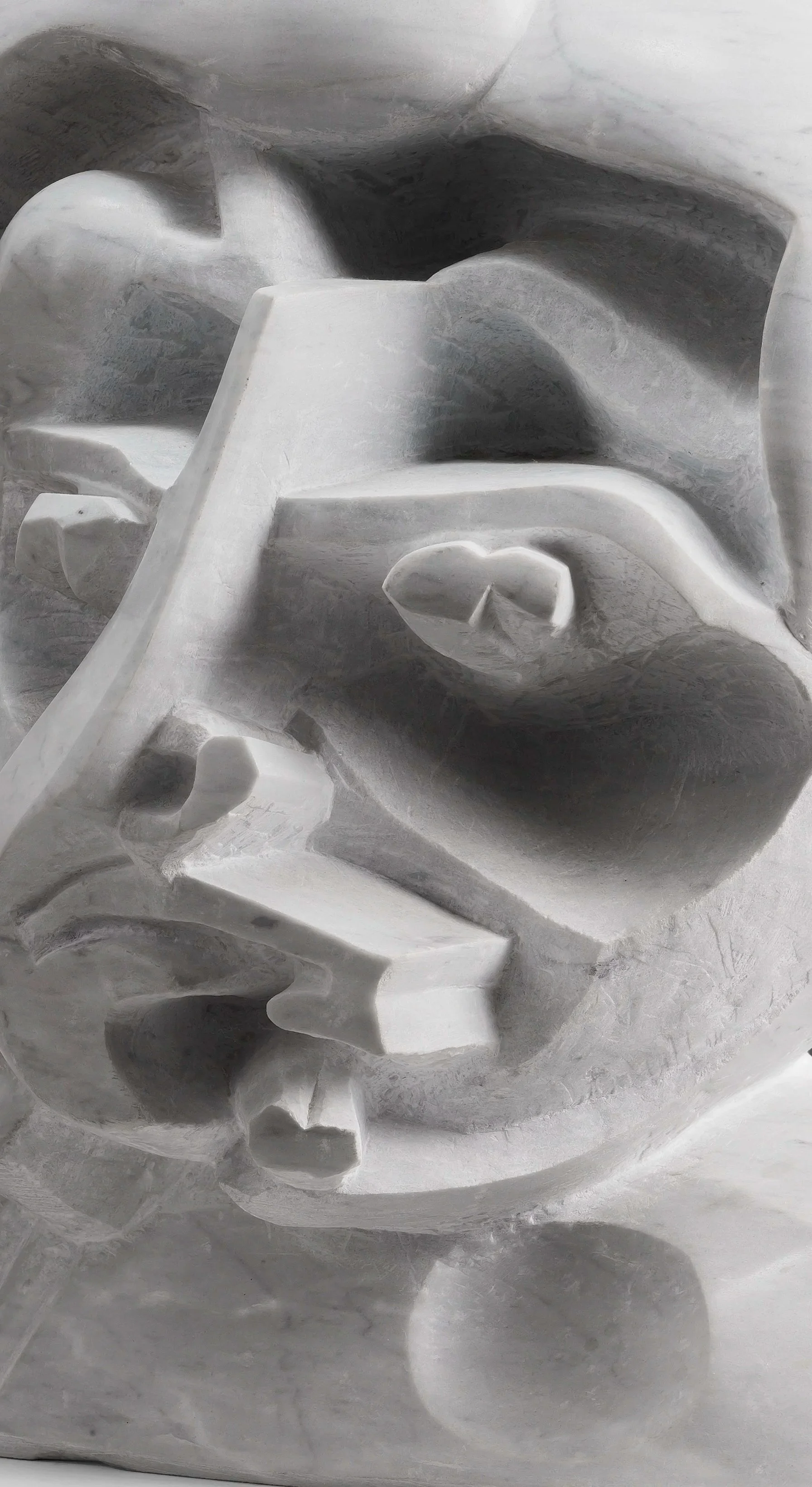 Sculpture en marbre représentant un visage humain avec des traits abstraits et stylisés.