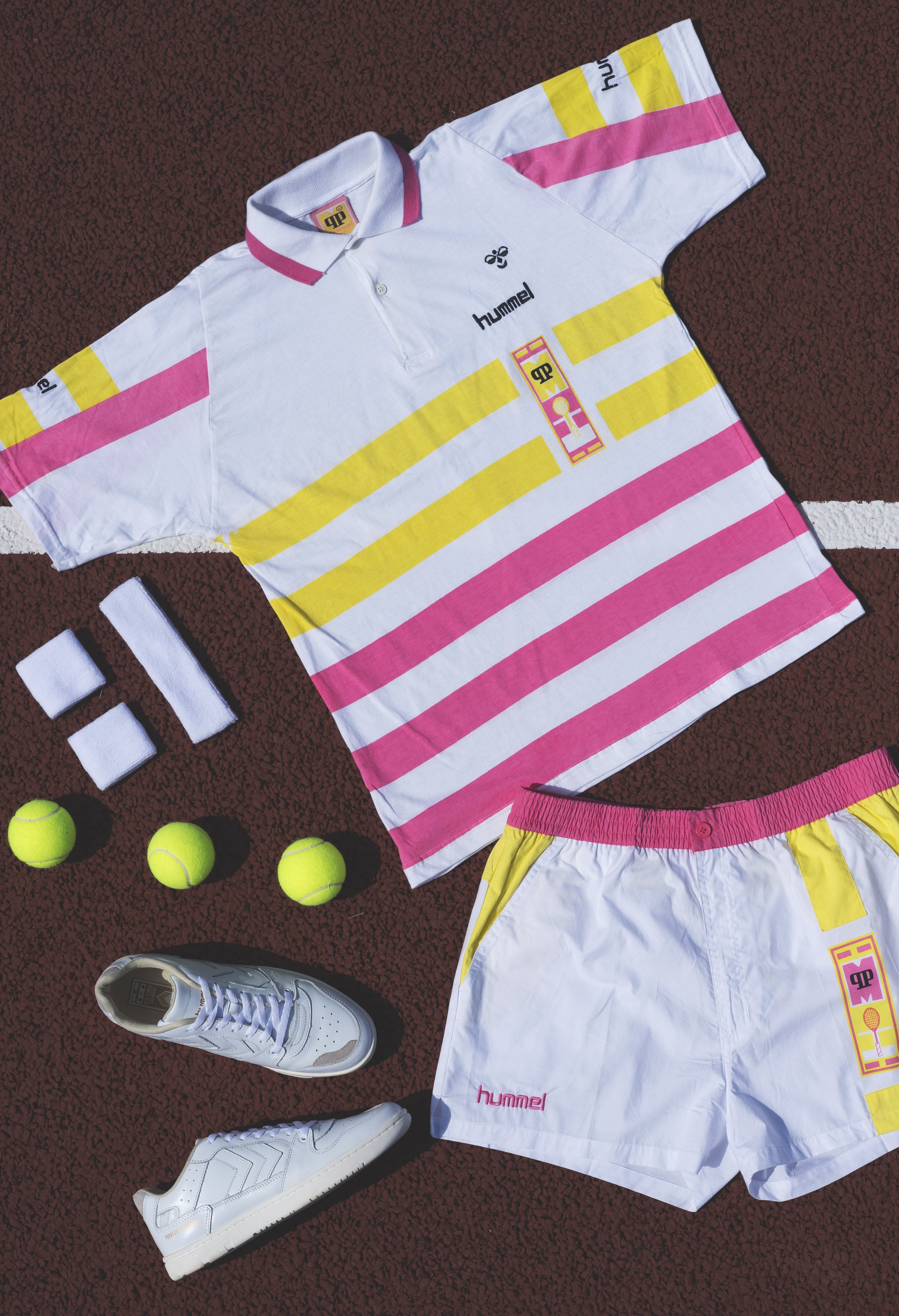 Vêtements de tennis, y compris une chemise blanche à rayures roses et jaunes, un short blanc avec des rayures jaunes et roses, et des chaussures de sport blanches, ainsi que des balles de tennis jaunes - marque HUMMEL