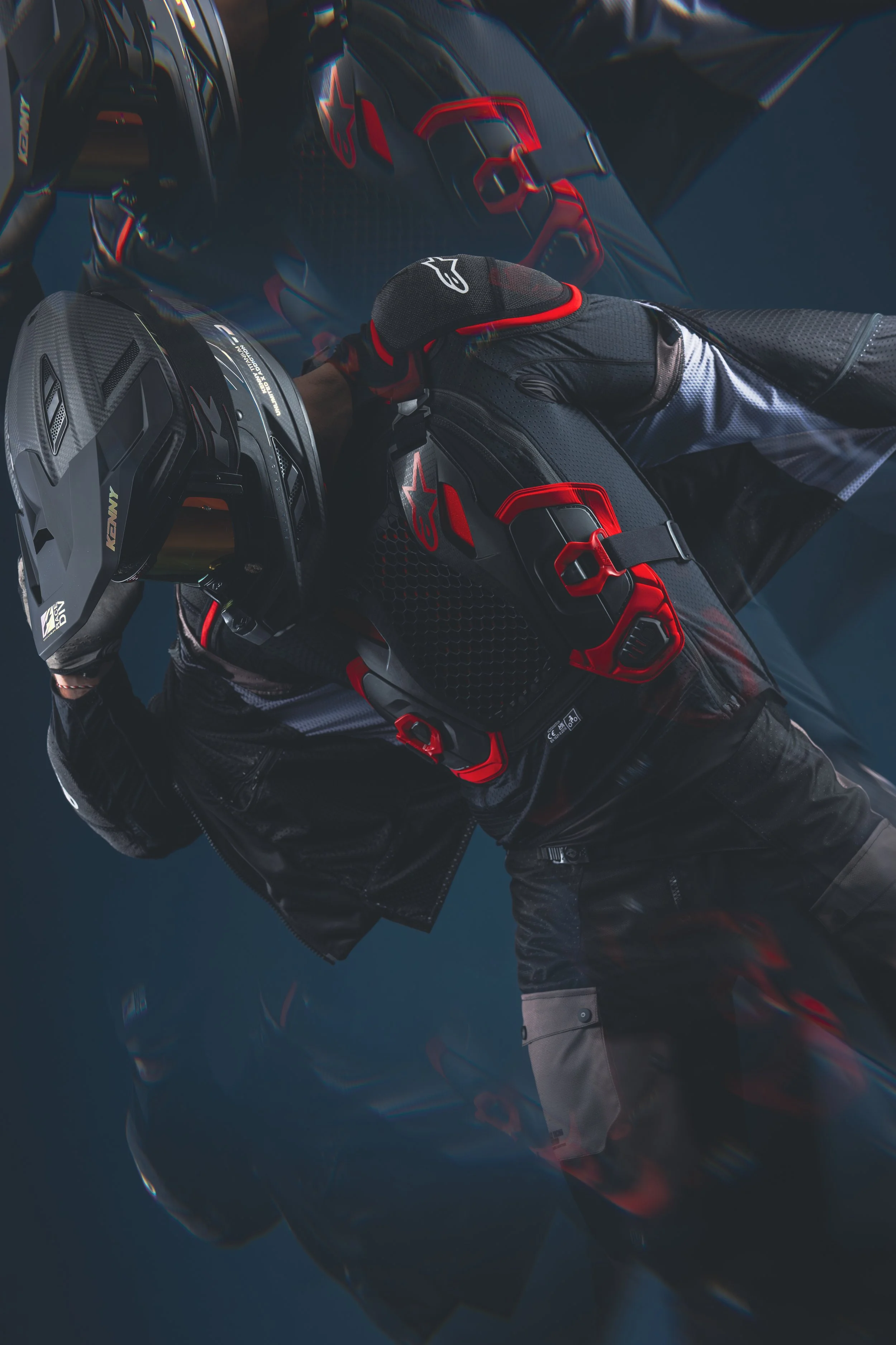 Un pilote de moto prêt à rouler, portant un casque, une veste de protection avec logo Alpinestars, et des gants, à l'intérieur d'un véhicule de course ou d'une moto de sport.