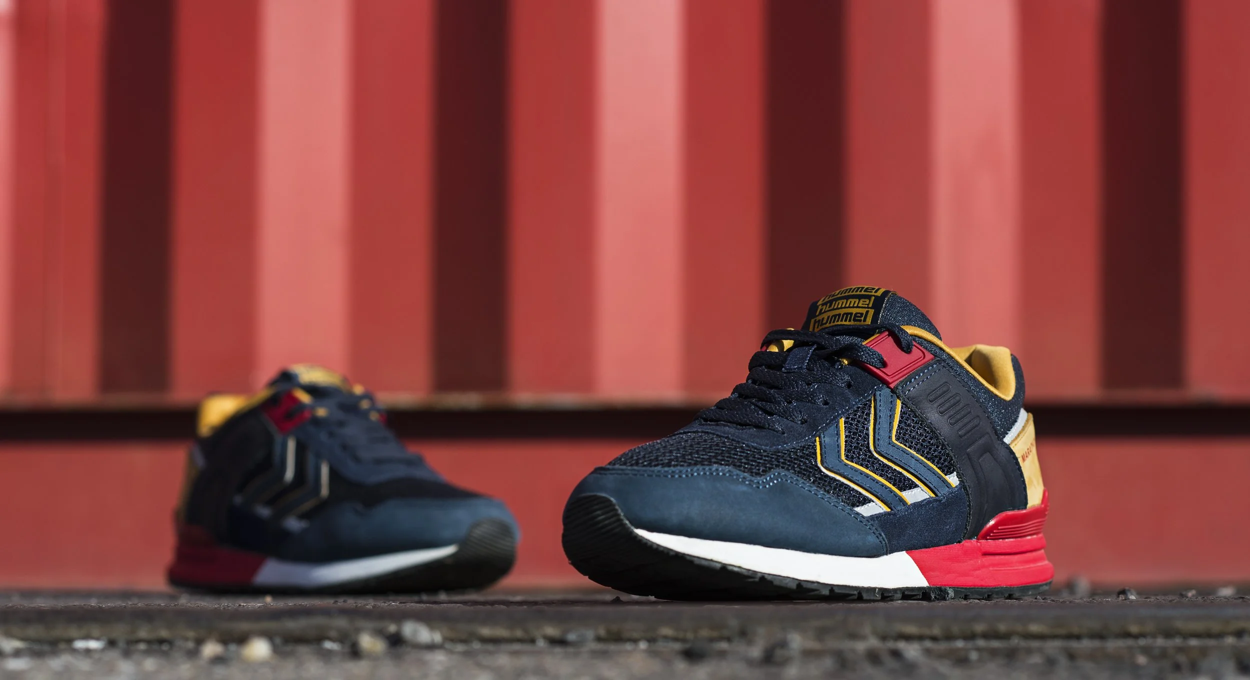 Une paire de baskets de sport colorées posée sur le sol, avec un fond rouge