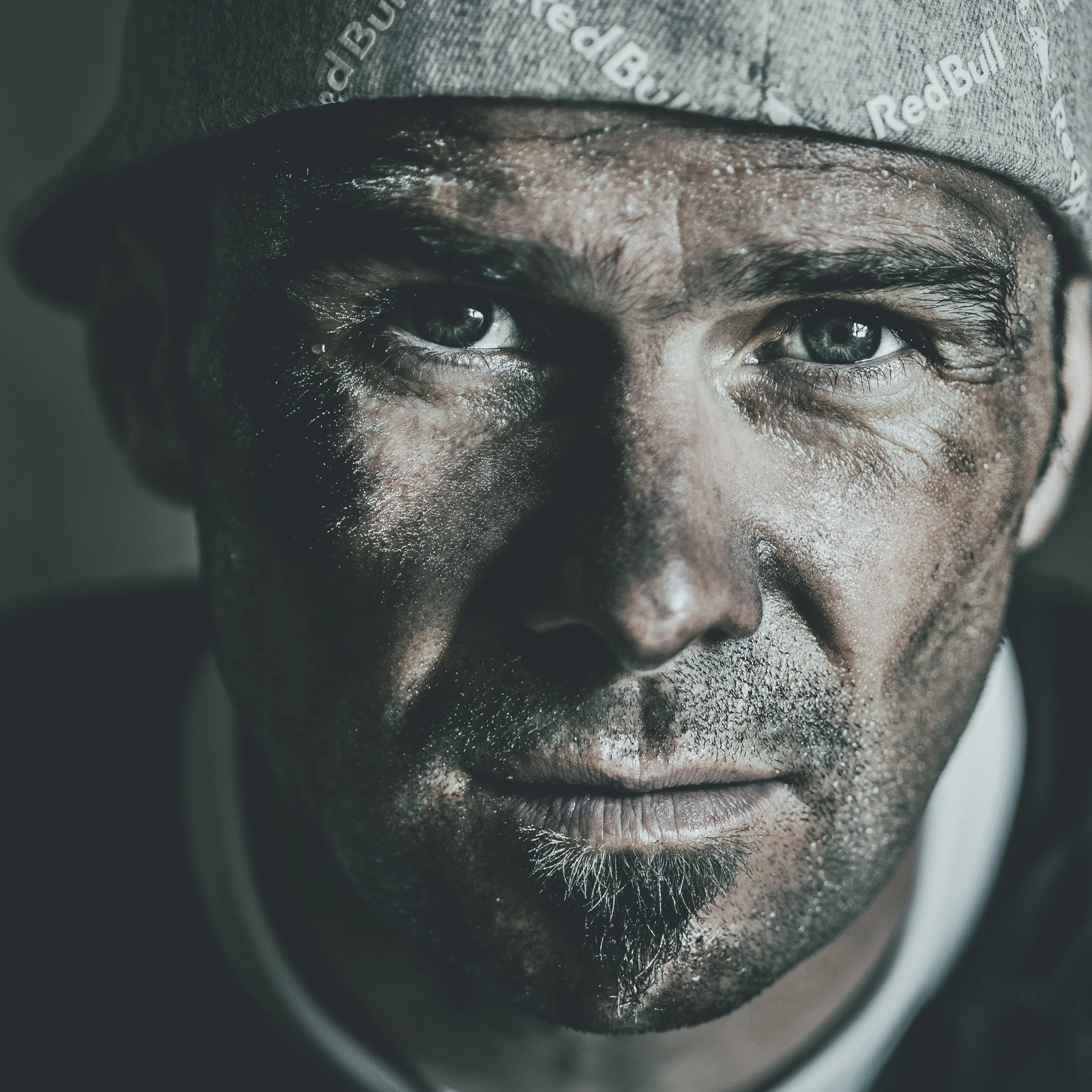 Gros plan d'un œil humain avec des cils longs et des détails de la peau environnante, vue en gros plan, avec un tissu gris avec des logos Reebok en arrière-plan.