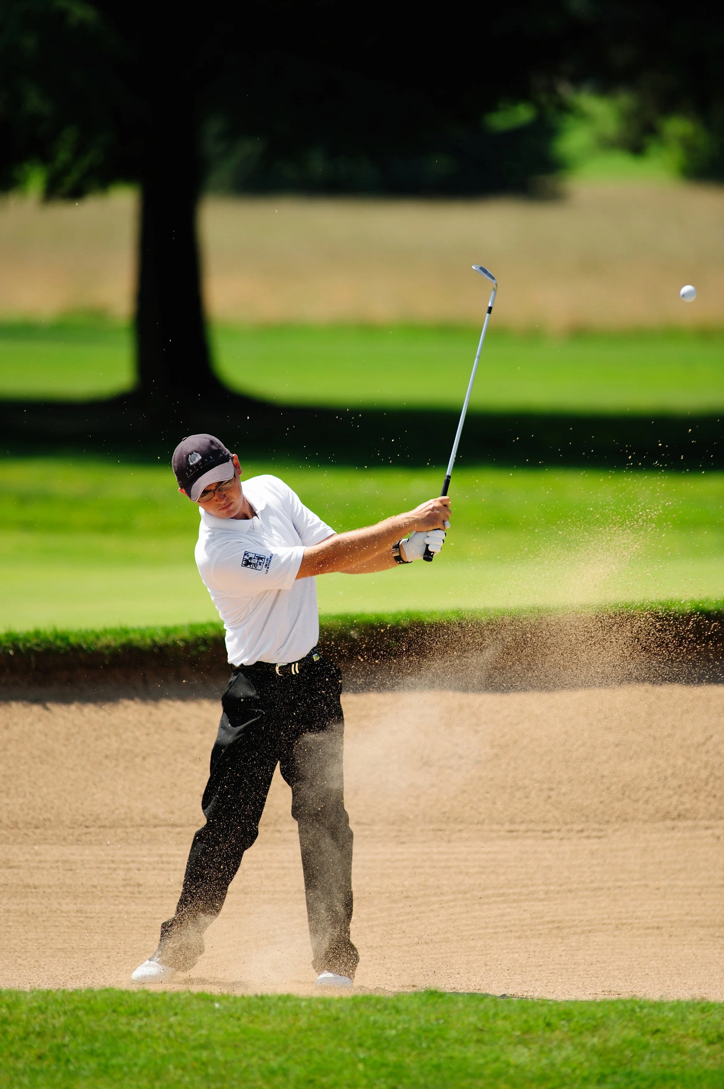 Un golfeur en train de faire un chip shot depuis le bunker sur un parcours de golf.