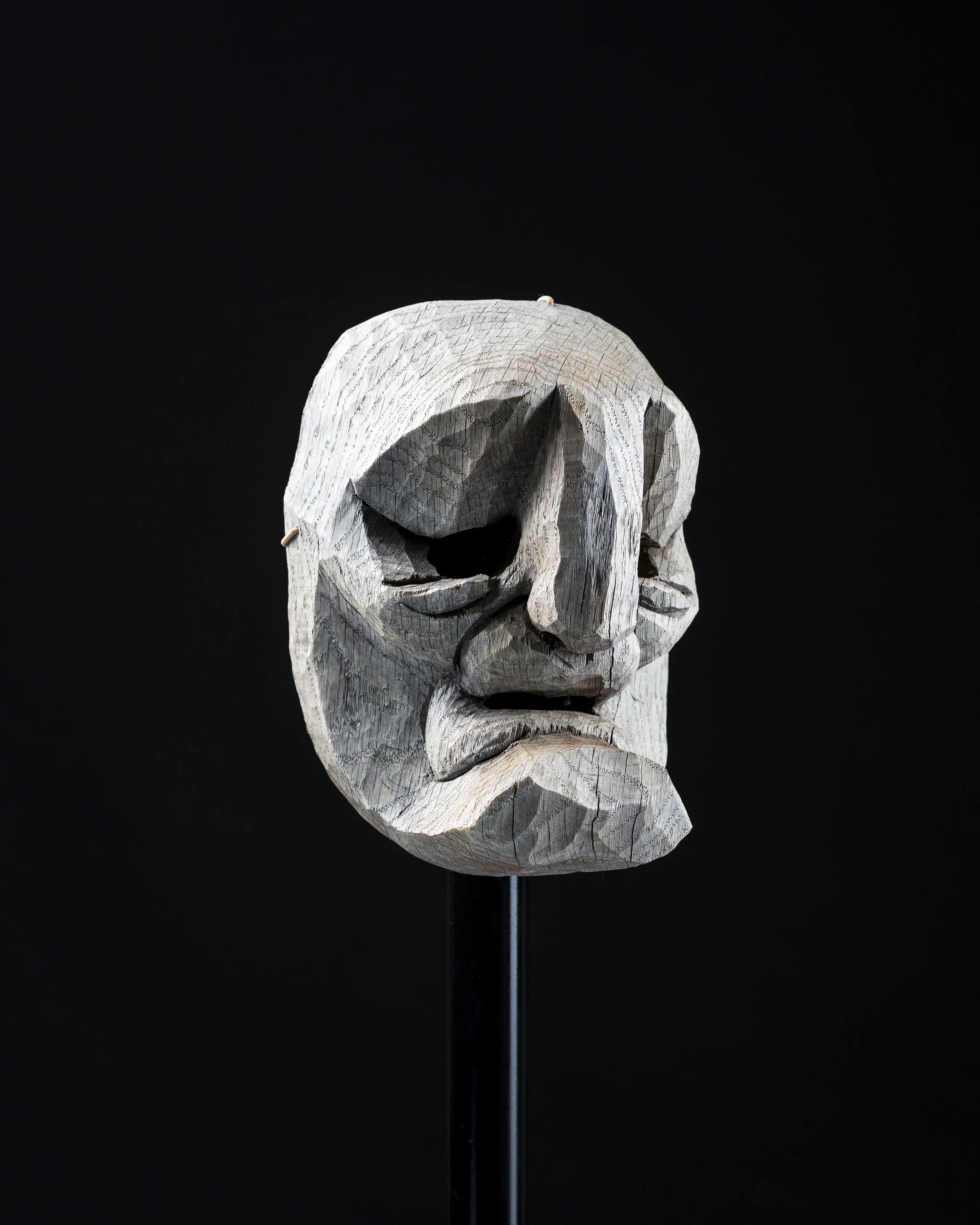 Tête de sculpture en bois sculptée à la main sur fond noir.