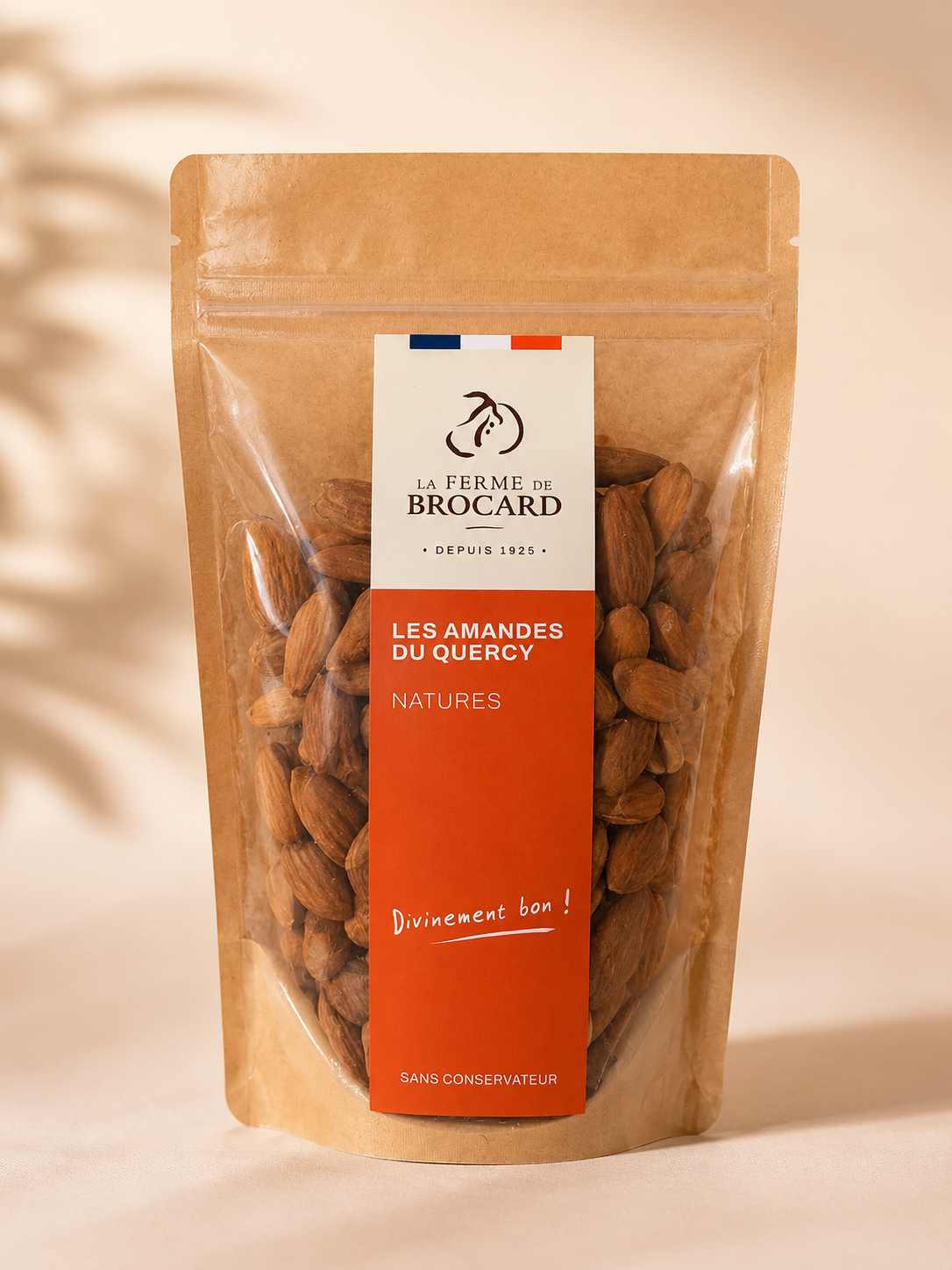 A resealable brown paper bag of almonds with a white and orange label from La Ferme de Brocard, displaying almonds and French text.