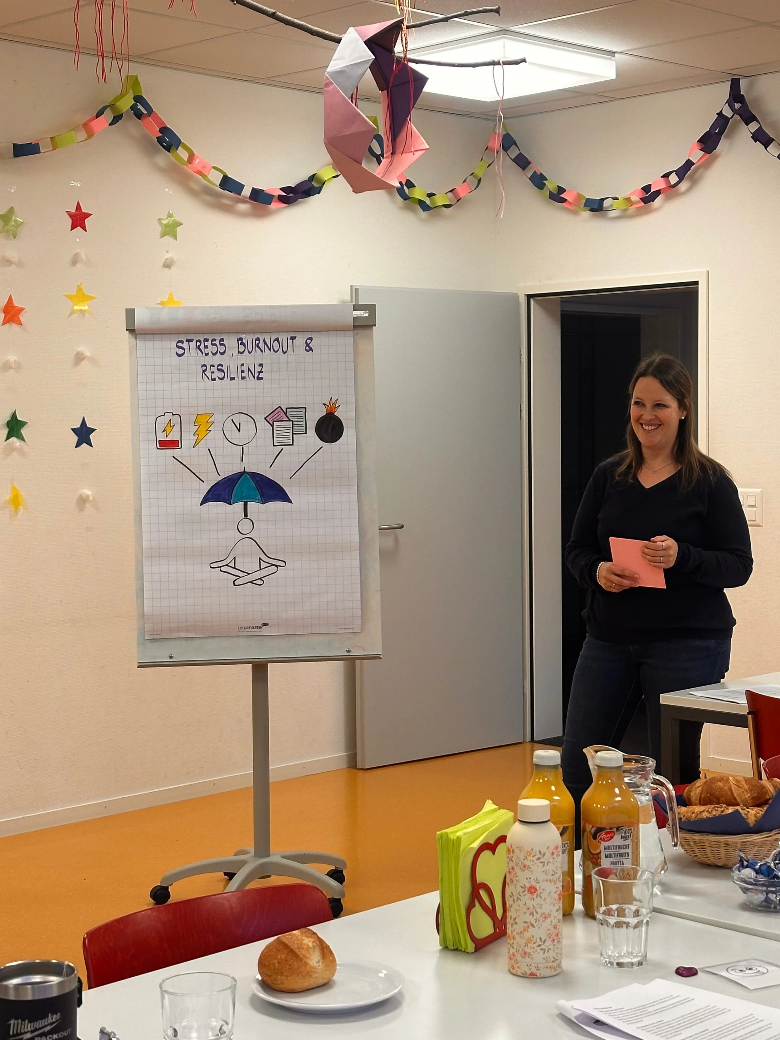 Aline Schneider, diplomierte Coachin für mentale Gesundheit, Stressprävention und Burnout-Prävention für Unternehmen steht vor einem Flipchart und gibt einen Workshop für einen Ausbildungsbetrieb aus Graubünden.
