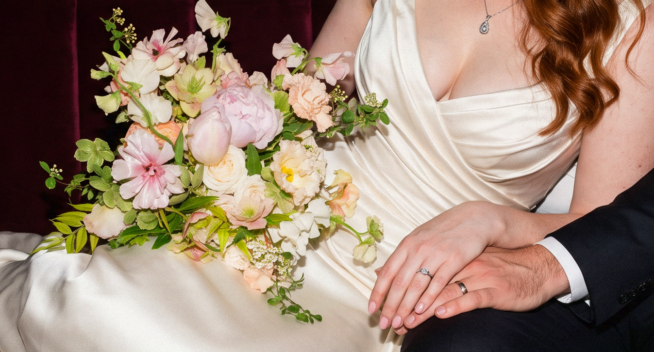 Flowers on lap of bride. Peach, pink and gentle greens on silk dress