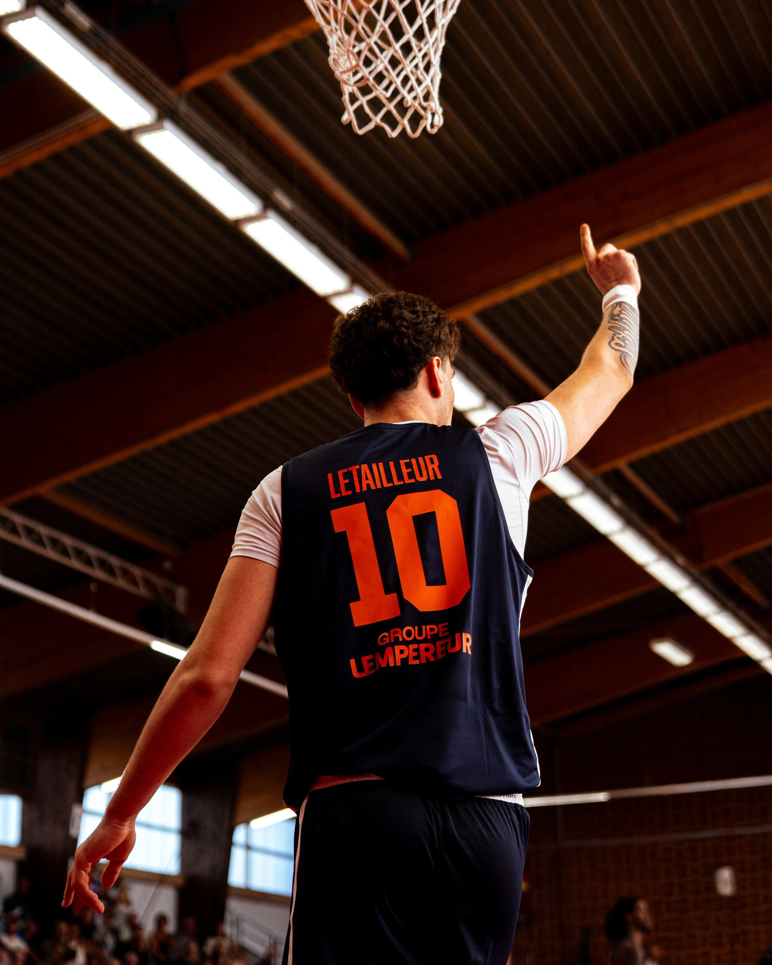 Un basketteur en action dans une salle de sport en bois, portant un maillot avec le numéro 10 et le nom 'Letaillieur'.