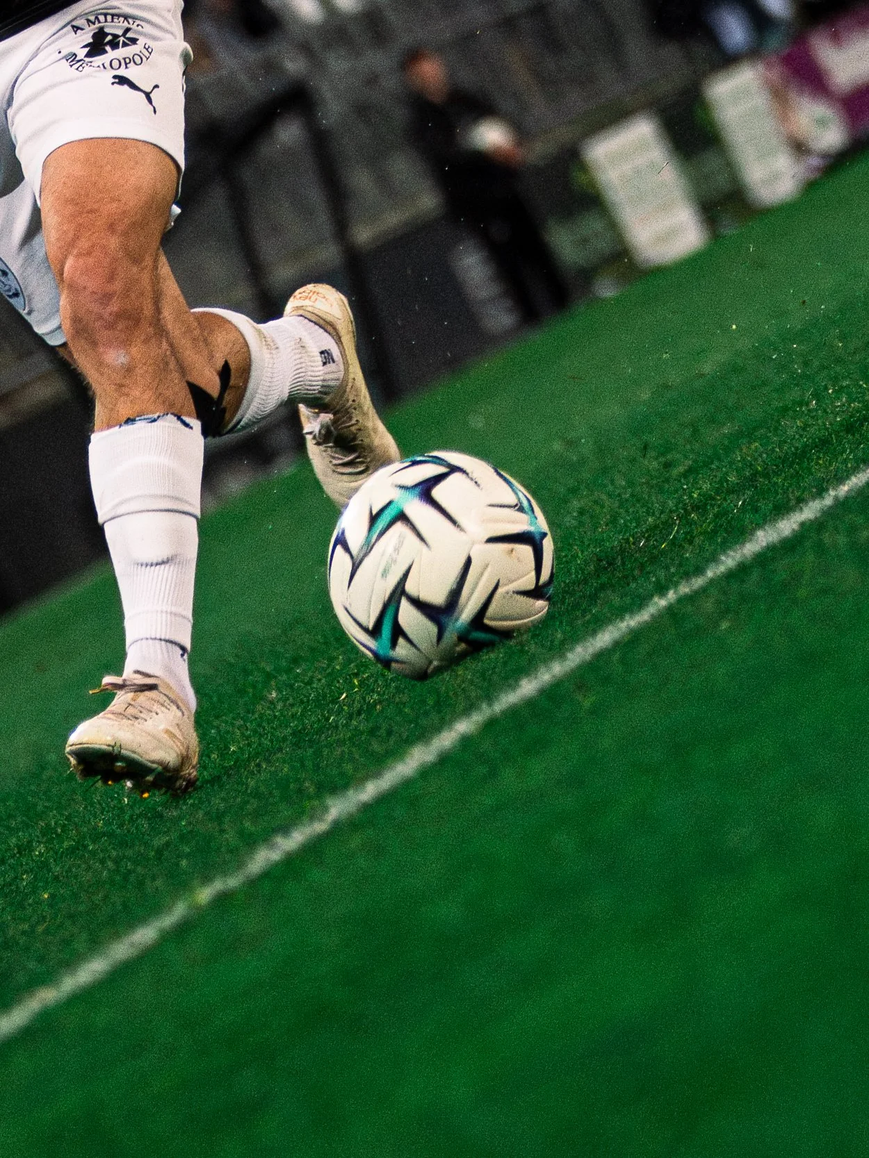 Un joueur de football en mouvement, frappant un ballon sur un terrain vert.