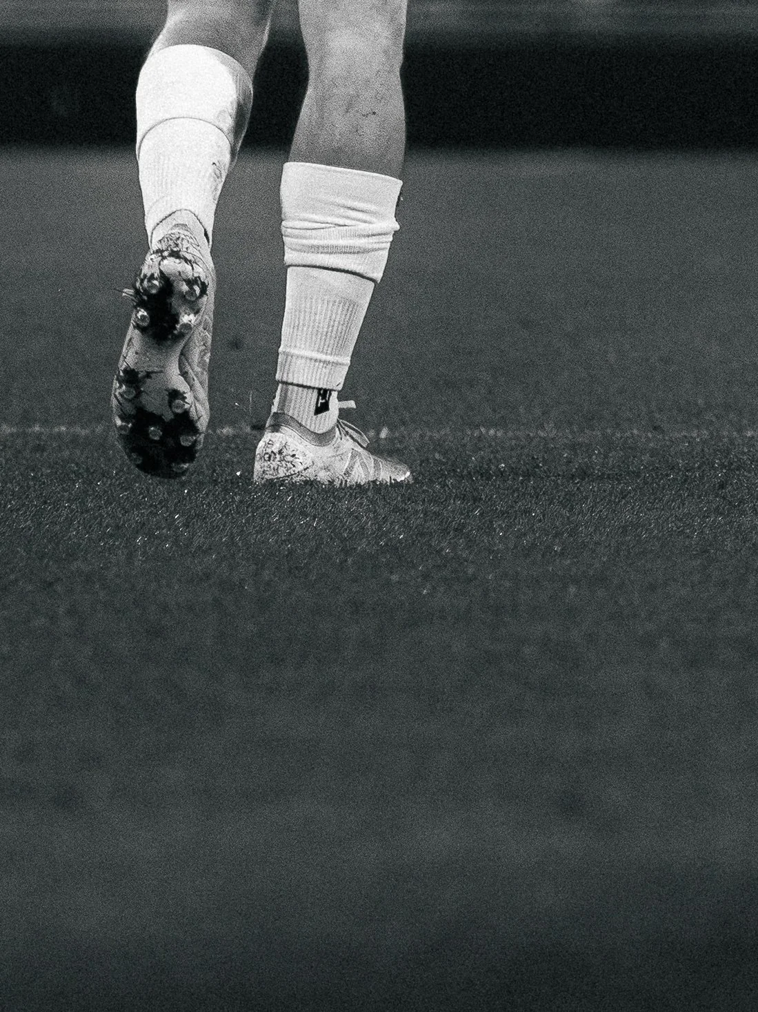 Un joueur de football, portant des chaussures de sport et des chaussettes, marche sur un terrain.