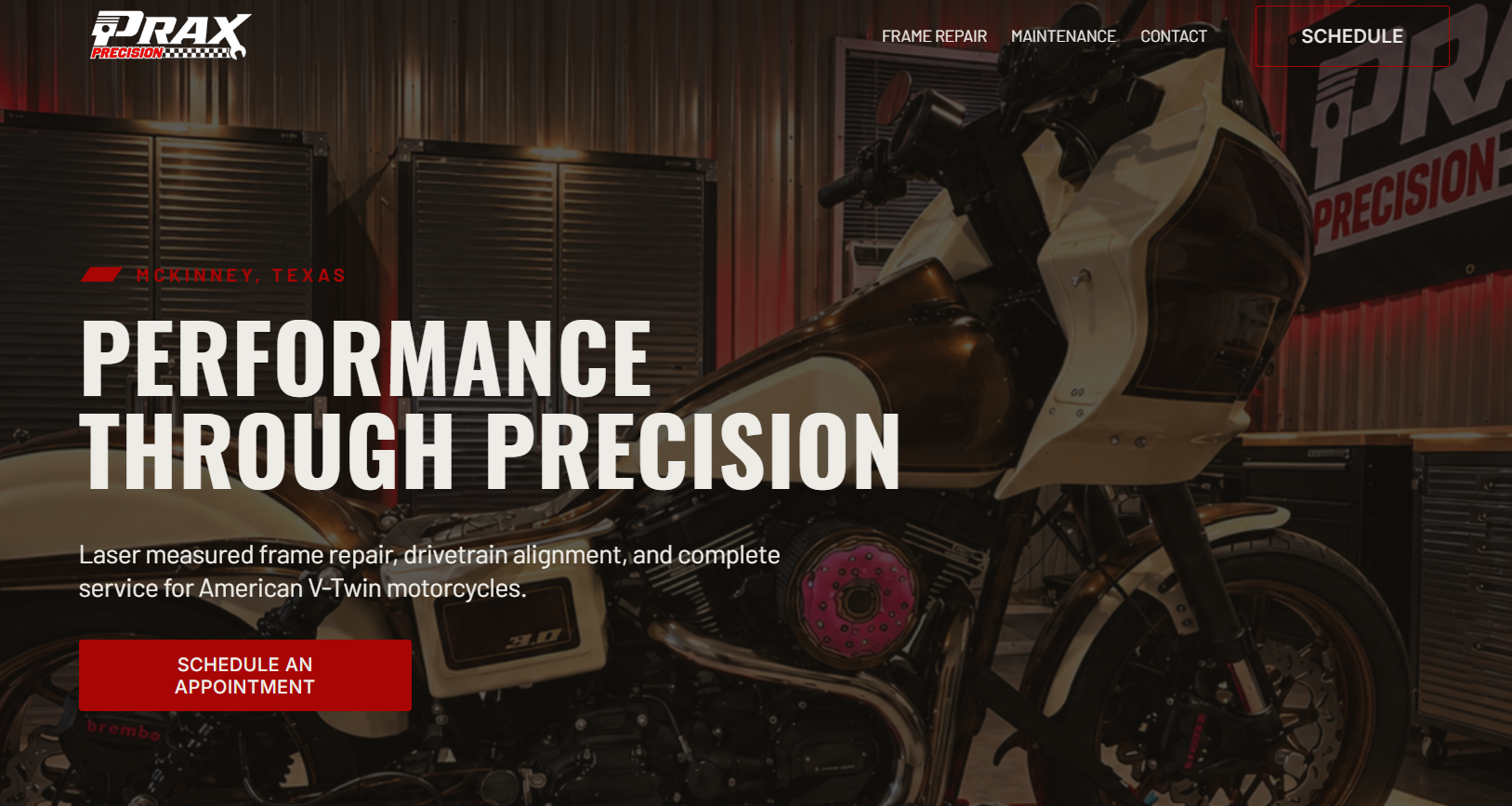 A motorcycle shop with a white and brown motorcycle in the foreground, black storage cabinets, and a banner with the company logo in the background that reads 'PRAX Precision.'