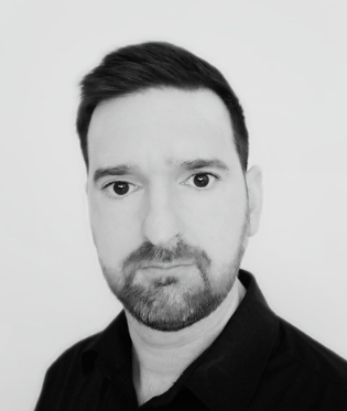 Black and white headshot of a man with short dark hair, a beard, and wearing a dark shirt.