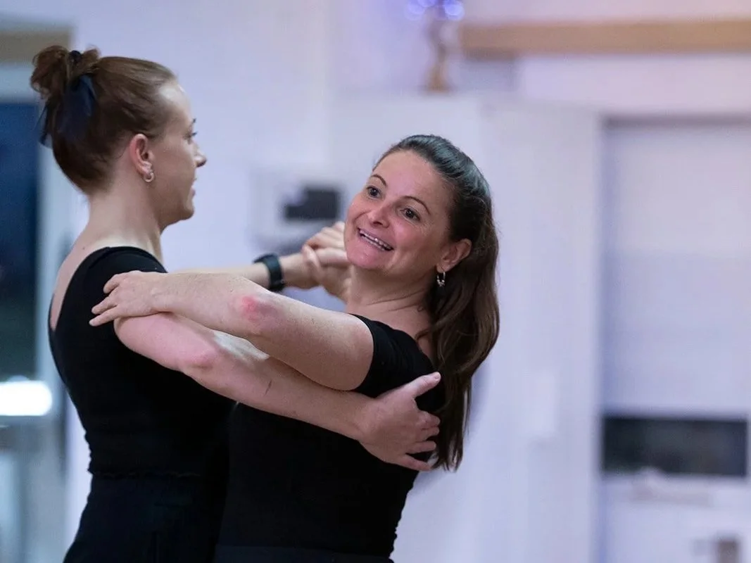 Two women dancing and smiling in a dance studio.