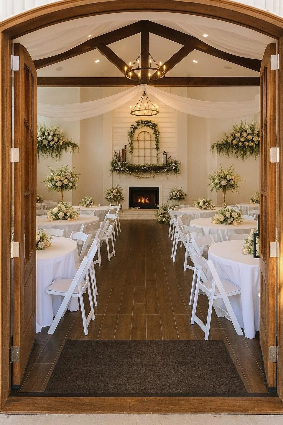 Elegant indoor wedding reception with white tablecloths, floral centerpieces, and a decorated fireplace.