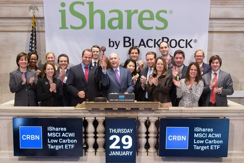 A group of people at the New York Stock Exchange celebrating the launch of iShares MSCI ACWI Low Carbon Target ETF on January 29th. The group is standing behind a platform with digital screens displaying the ETF details and the date. The background features a large banner with the iShares logo and a U.S. flag.