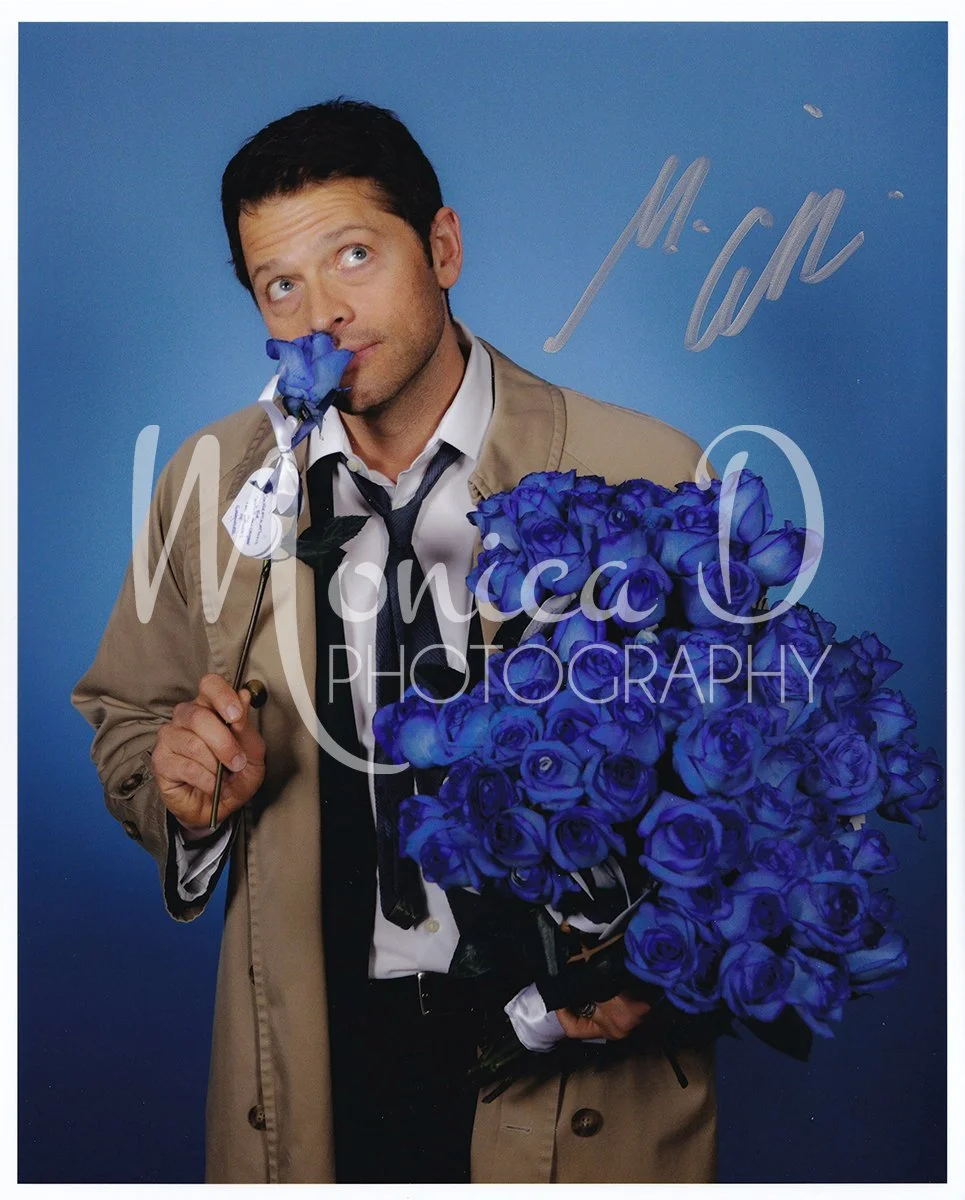 Misha Collins in costume as his Supernatural character, Castiel.Misha is holding 100 special blue roses, gifted to him to celebrate 100 Supernatural episodes in which Castiel appeared.
