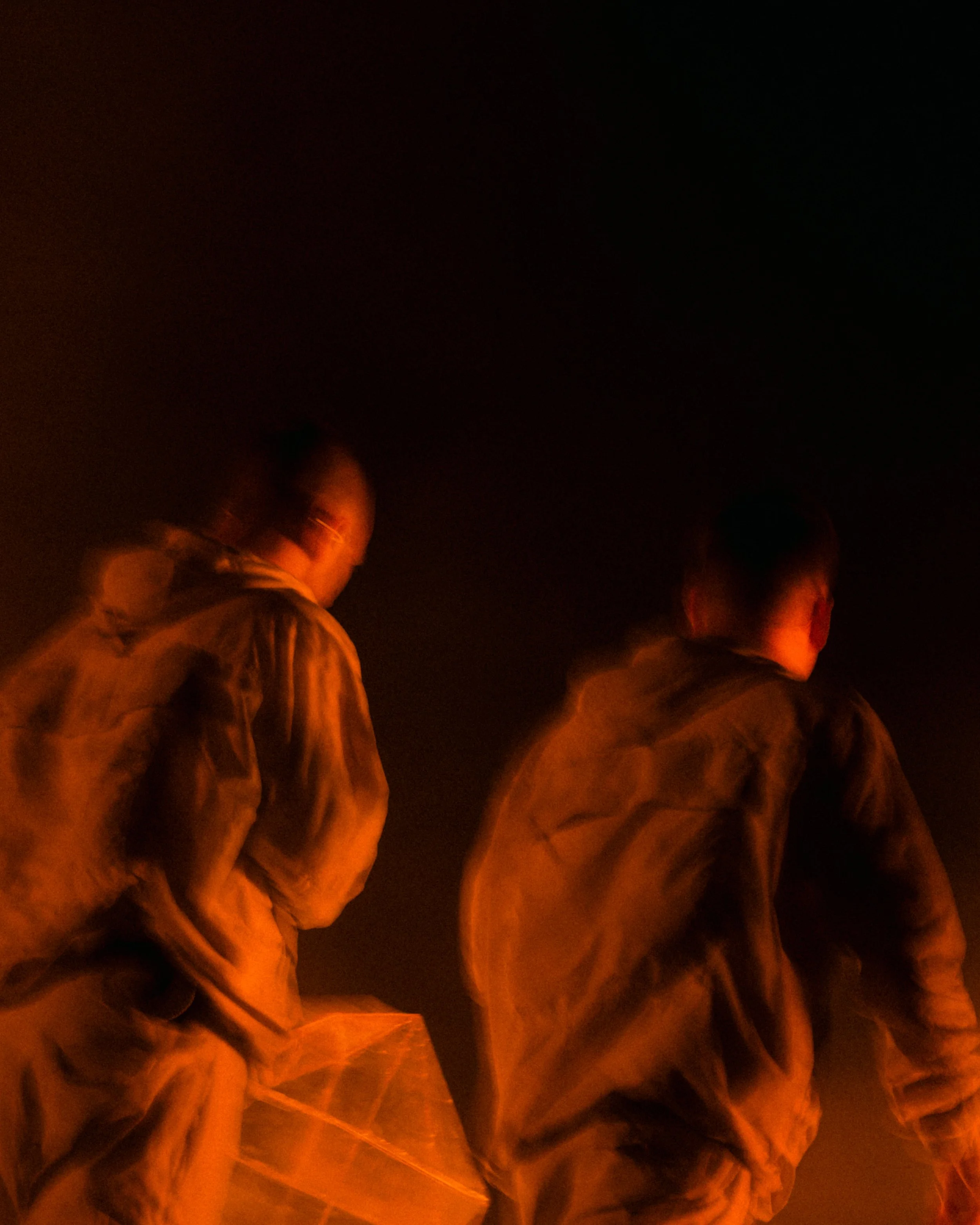 People standing in a dark environment illuminated by a warm, orange glow.
