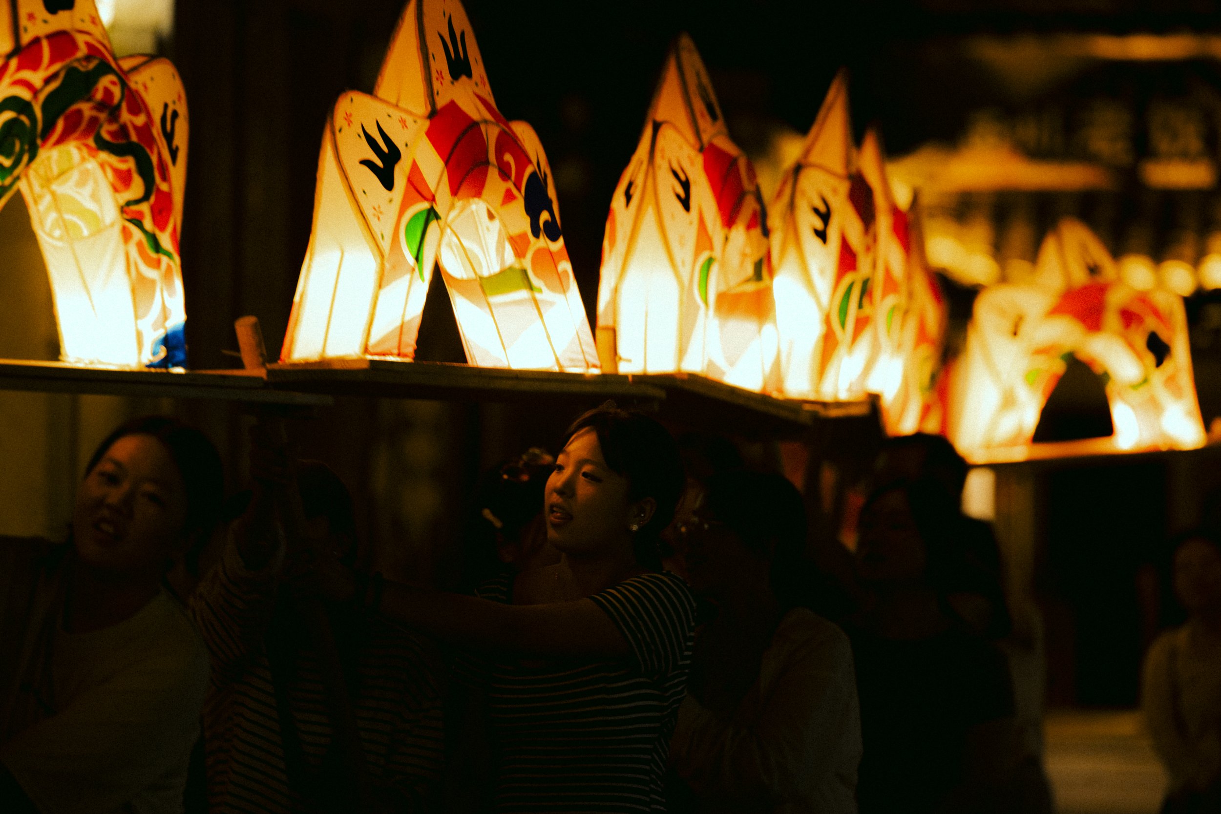 People observing illuminated paper lanterns with dragon designs at night.