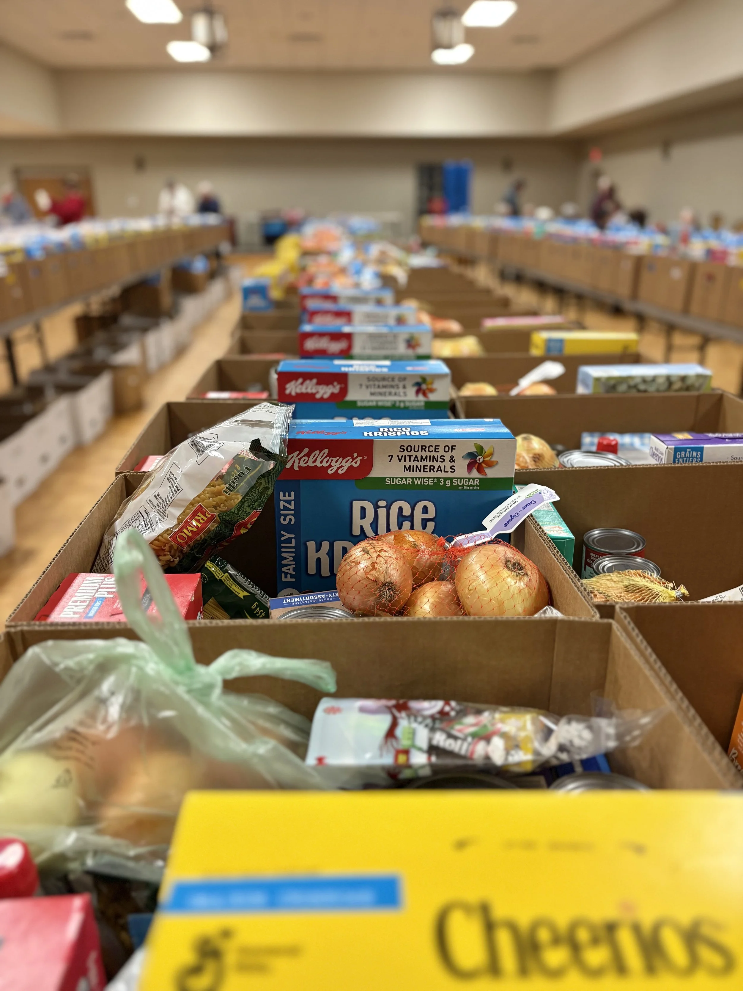 Tables filled with various food items and groceries in a community center or donation area.