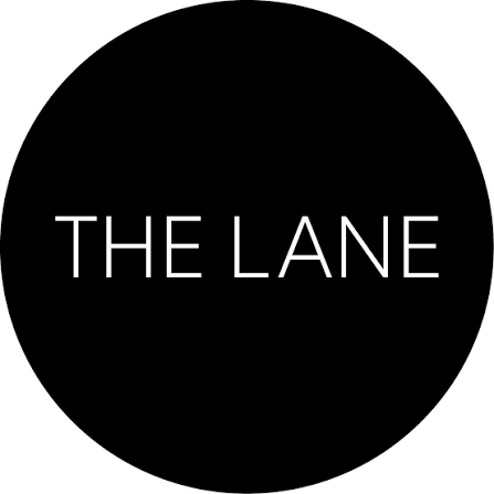 A black circular logo with the text 'THE LANE' in white capital letters.