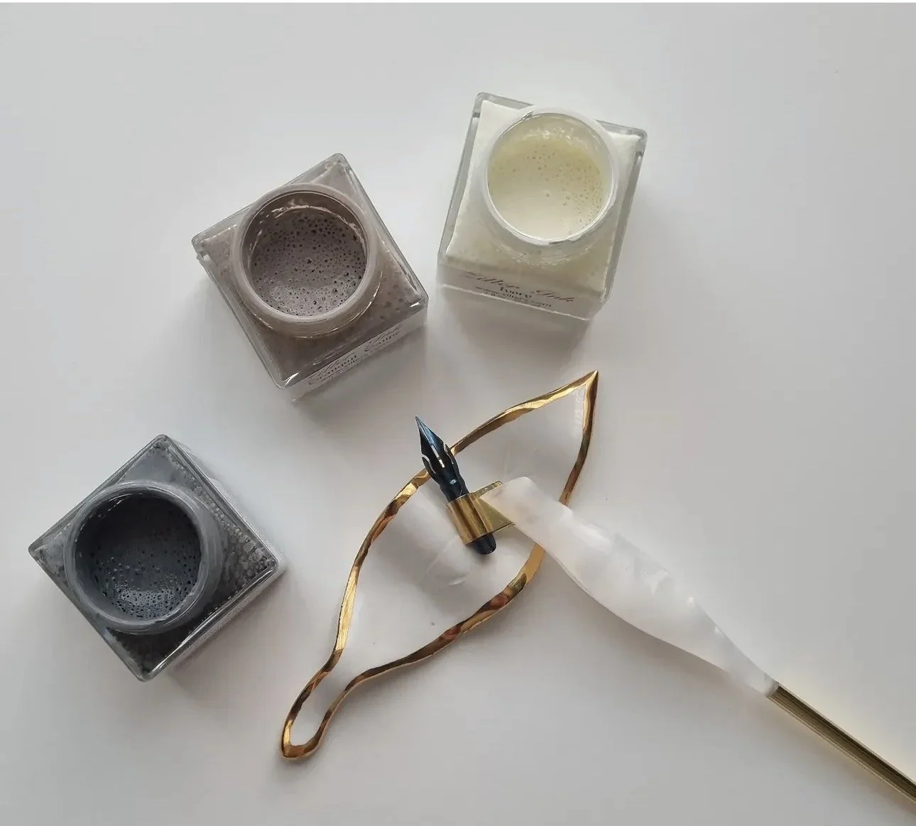 Nail polish bottles and a nail art brush on a white surface with a gold and white handle.