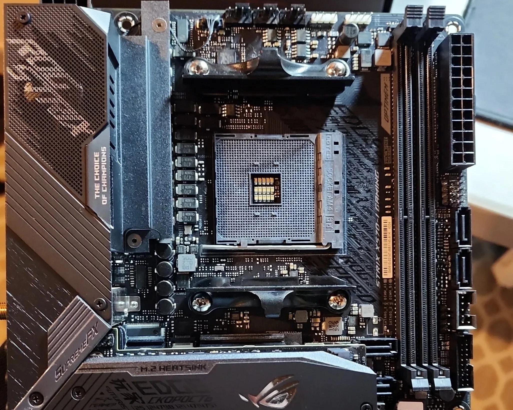 Close-up of a computer motherboard with various components, including a CPU socket, RAM slots, heatsinks, and power connectors.