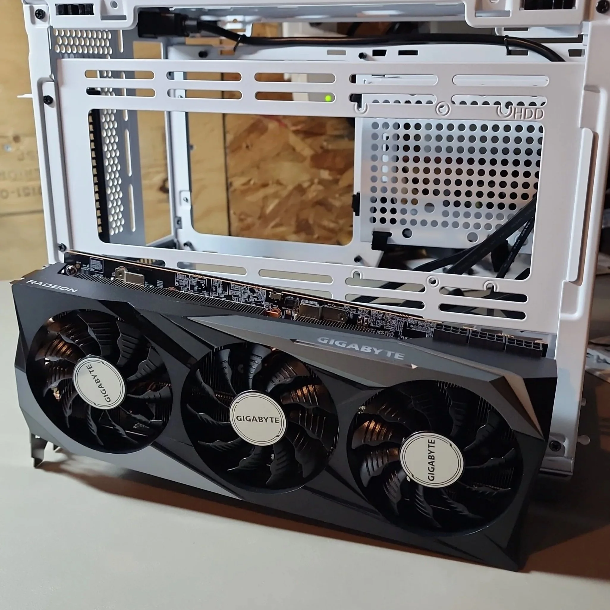 Part of an open computer case with a Gigabyte graphics card installed, showing cooling fans and internal components.