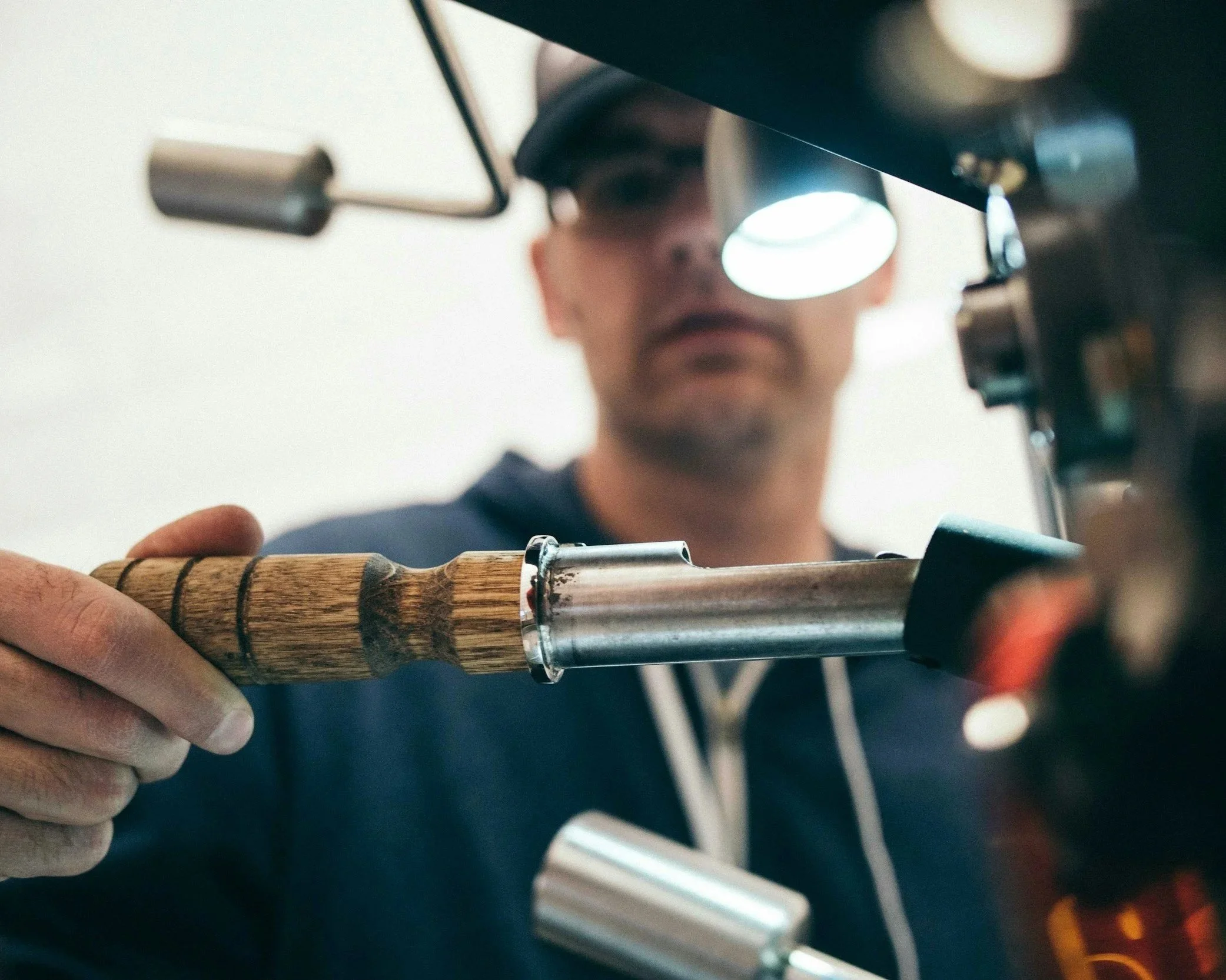Close-up of a person using a magnifier or microscope to examine a wooden and metal object.