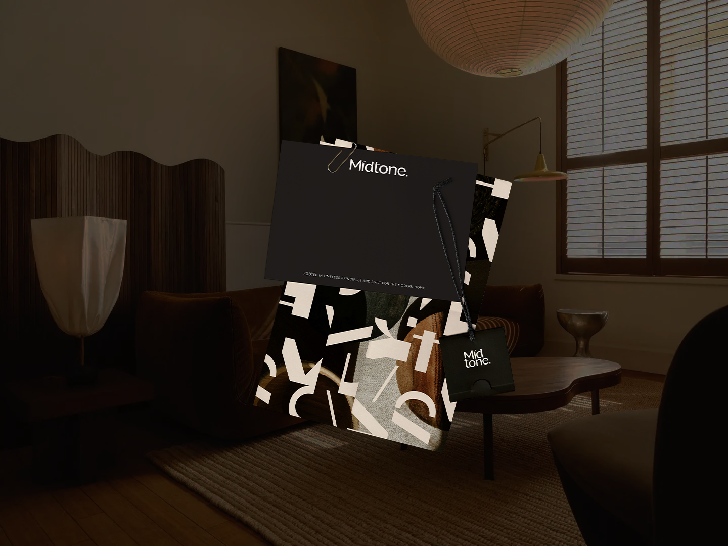 Indoor scene with a Midtone product box and packaging, featuring black and geometric design, in a living room with wooden furniture, window with blinds, and warm lighting.