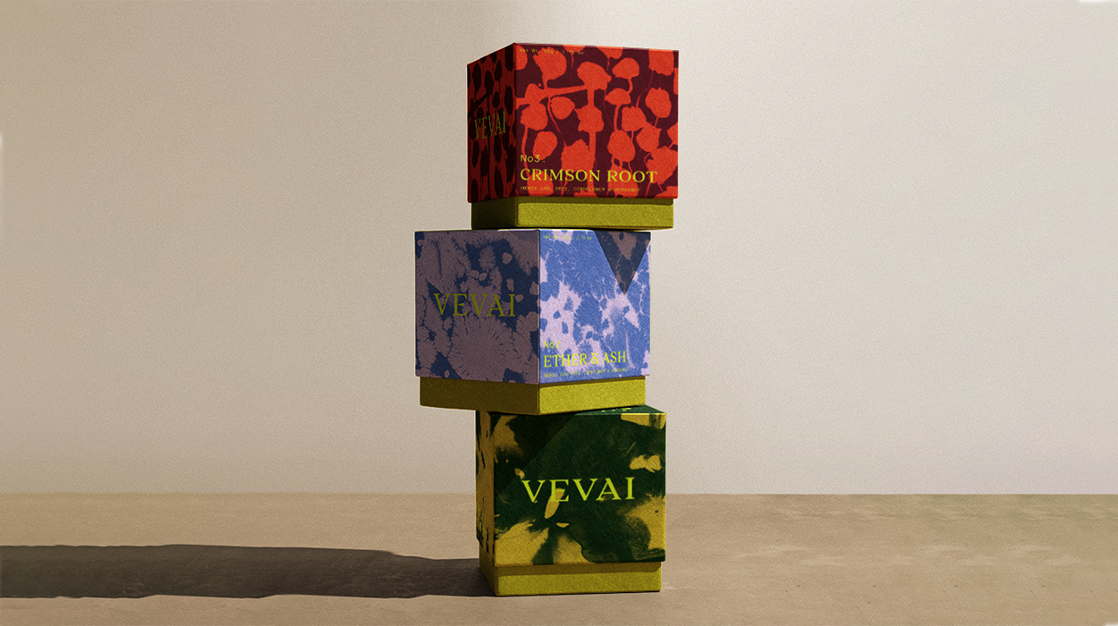 Three boxes stacked vertically, each with colorful, abstract patterns and text on the sides. The top box is red with red and orange designs and labeled "CRIMSON ROOT," the middle box is blue with purple designs and labeled "ETHER & ASH," and the bott