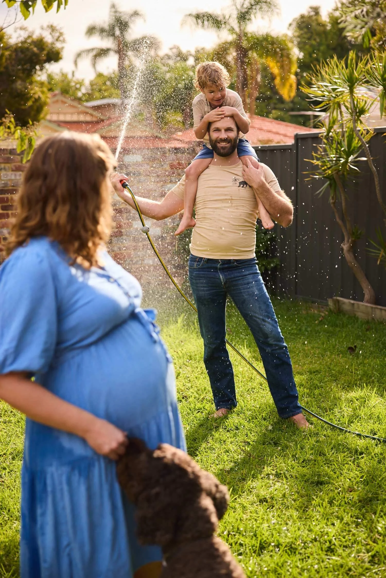 Family-playing-in-the-garden-with-water-hose-pregnant-woman-with-dog.jpg