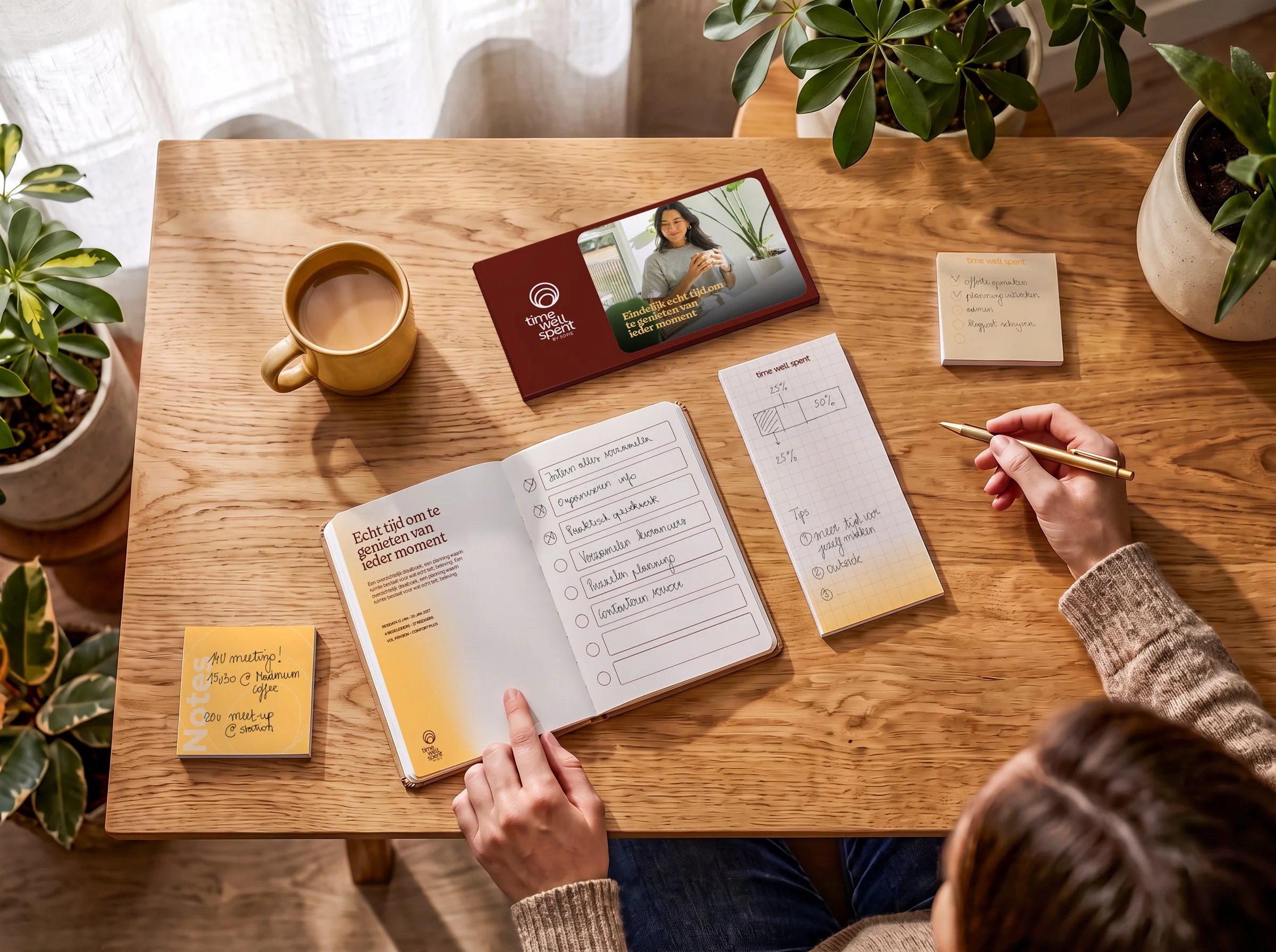 Een houten tafel met een open notitieboek, een pen in een hand, een kop koffie, een notitieblok met checklists, een map met een afbeelding van een vrouw die lacht en een plantenbak met groene planten.