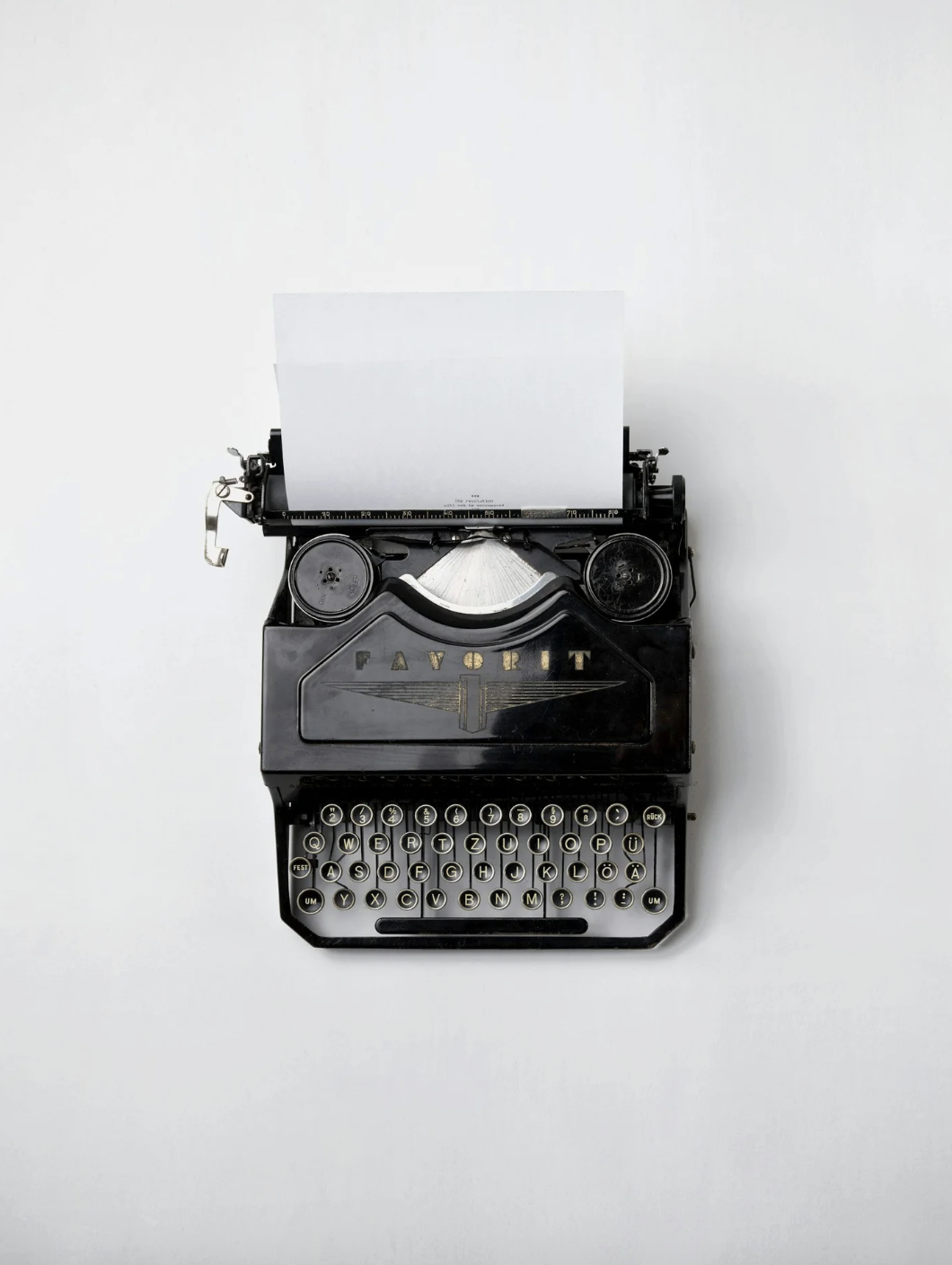Black vintage typewriter with a blank sheet of paper on a white background.