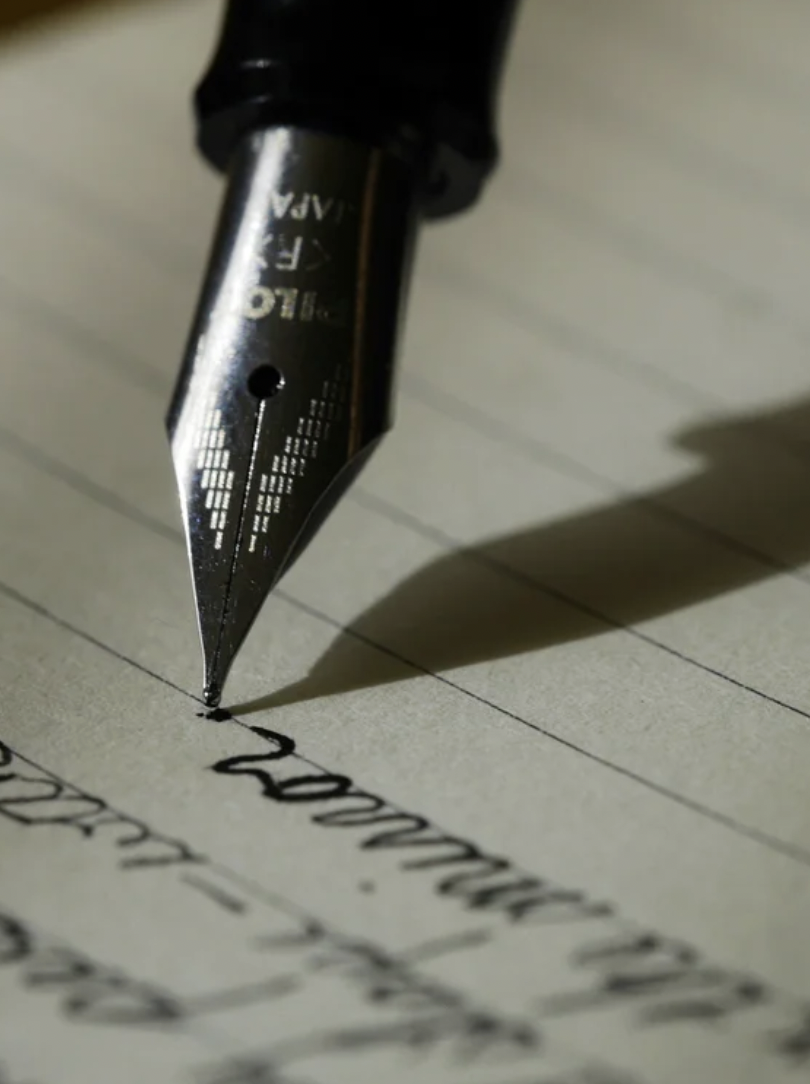 Close-up of a fountain pen writing on lined notebook paper.