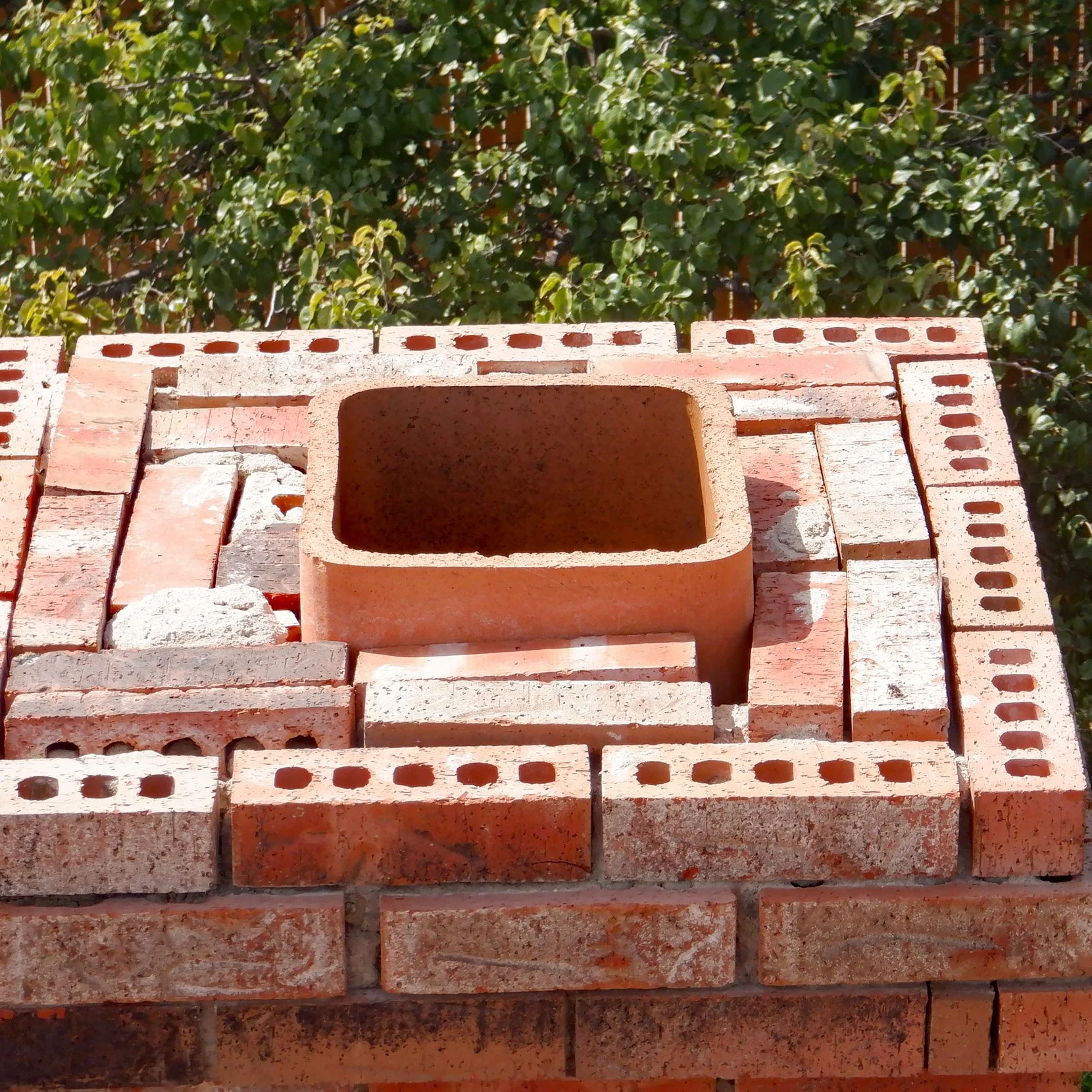 Completely eroded and missing fireplace chimney crown wash mortar with loose bricks and a missing rain cap spark arrestor found during a home inspection.