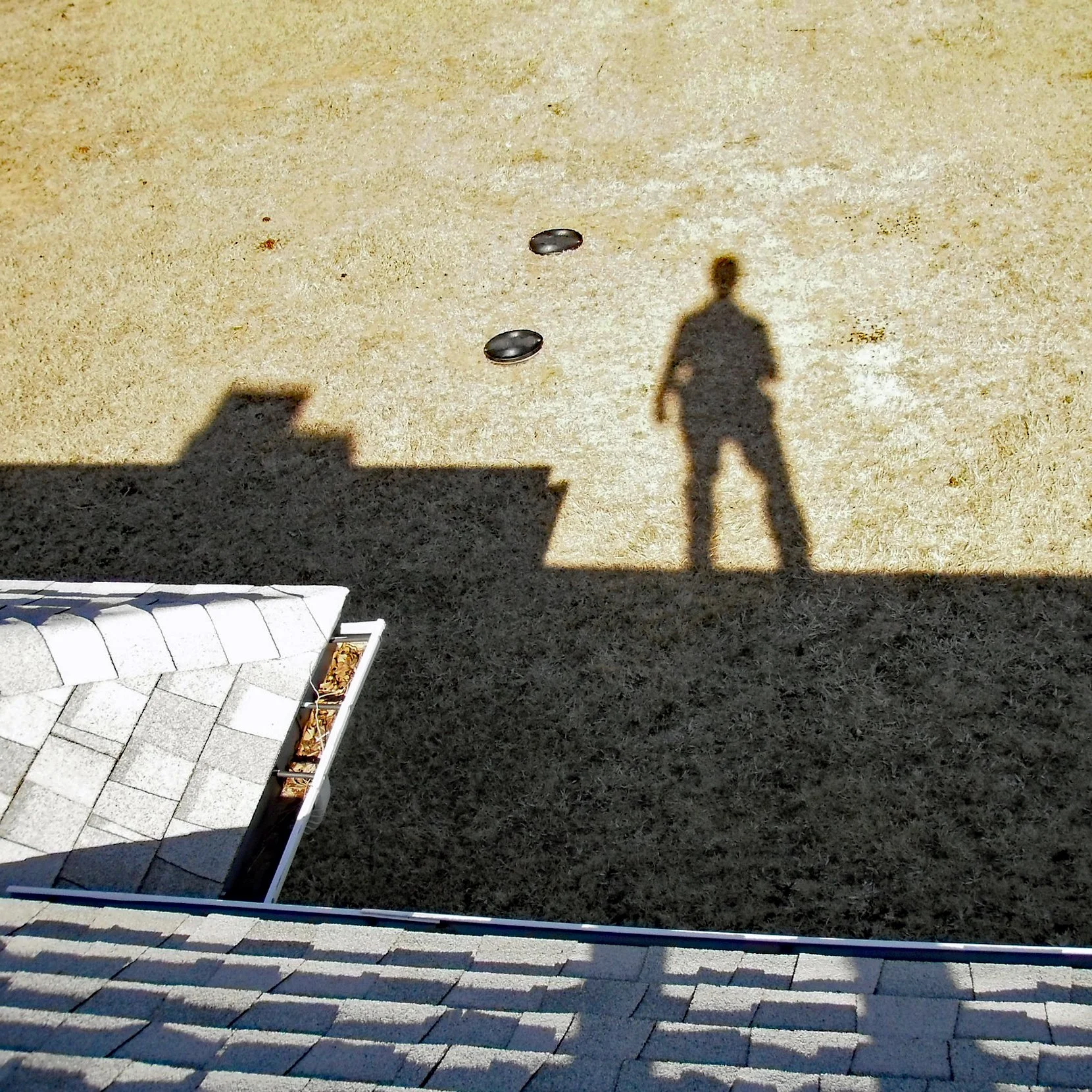 Shadow silhouette of a home inspector on the roof of a house.