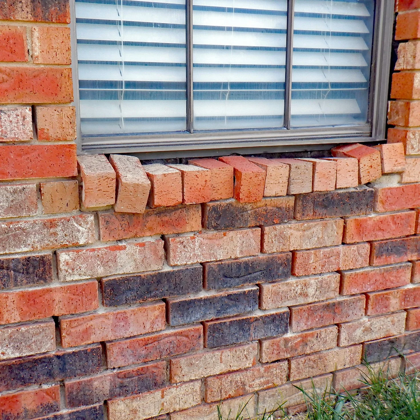 House exterior brickwork wall with significant mortar erosion loss and loose bricks found during a home inspection.