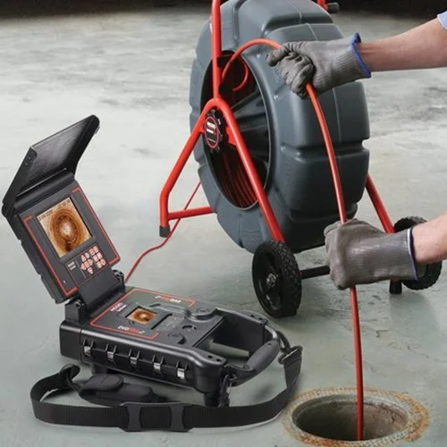 Plumbing inspector testing a sewer line using a portable inspection camera.