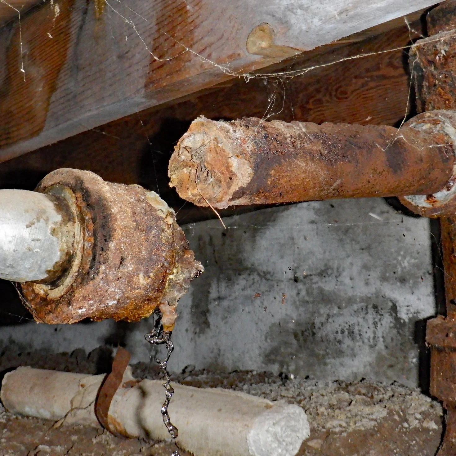 Broken and disconnected cast iron sewer drain pipe and leaking water in the crawlspace of a pier and beam foundation house found during a home inspection.