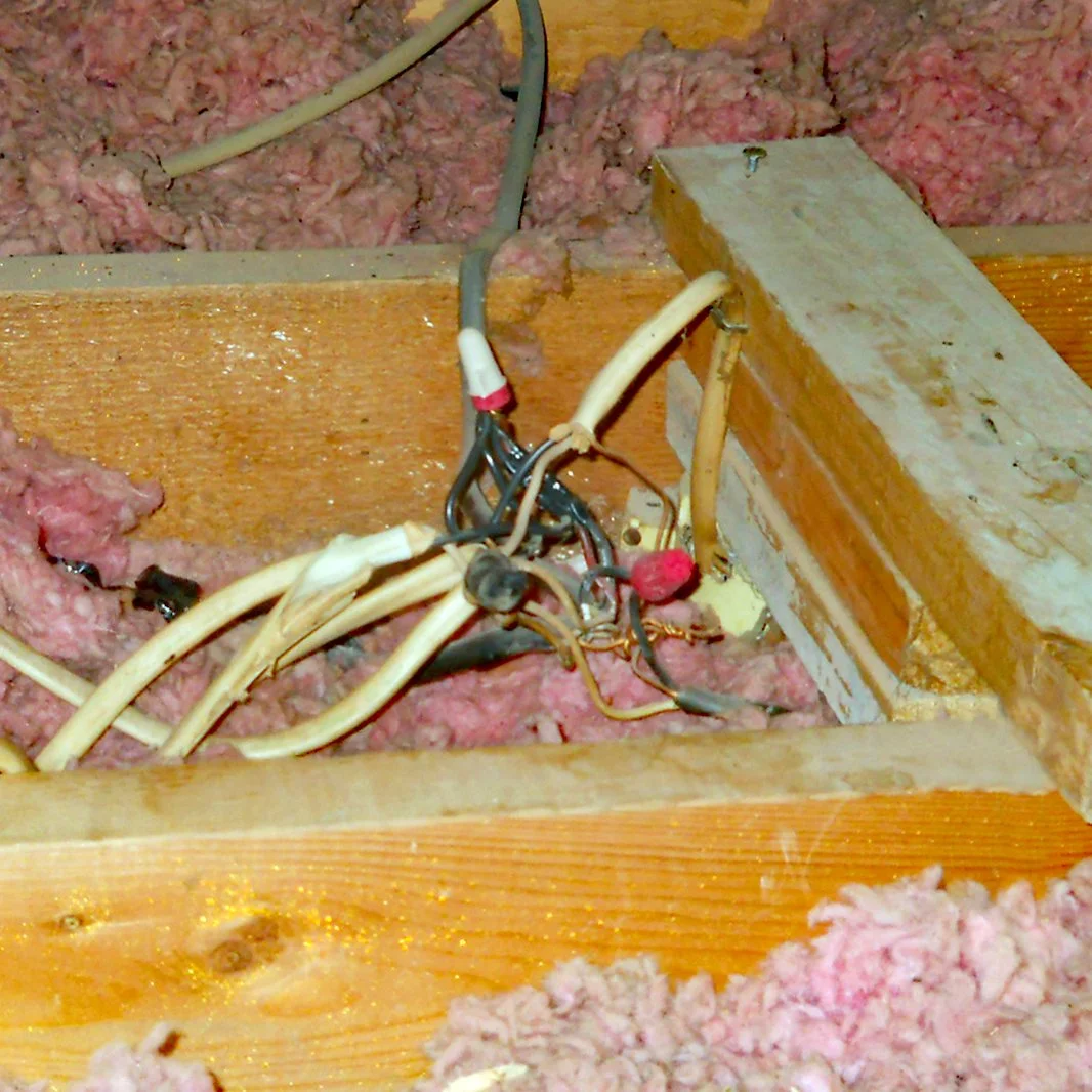 Electrical wiring splice no properly or safely contained in a junction box in a house attic space found during a home inspection.