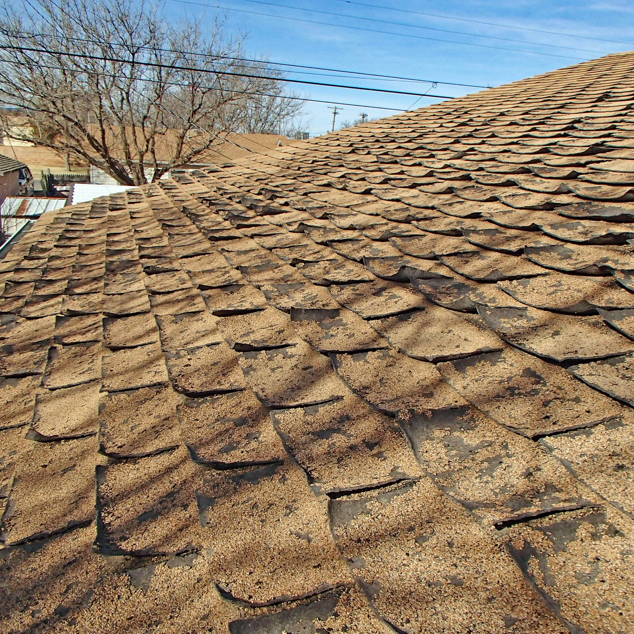 House asphalt composition roof with significant hail damage, granule loss and curling shingles from age found during a home inspection.