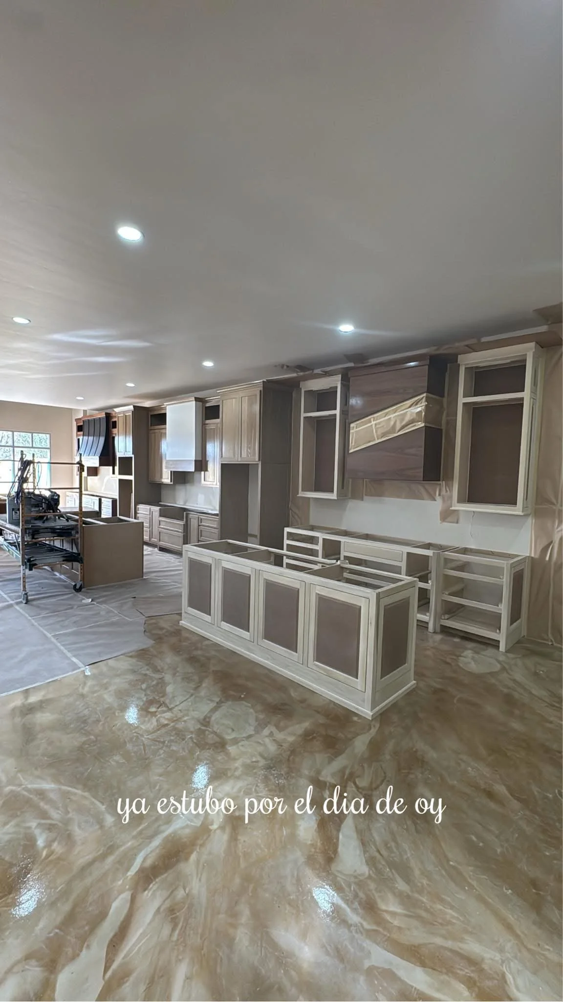 Interior of a house under construction, showing newly installed kitchen cabinets and a polished marble floor, with a caption in Spanish that reads 'ya estubo por el dia de oy.'