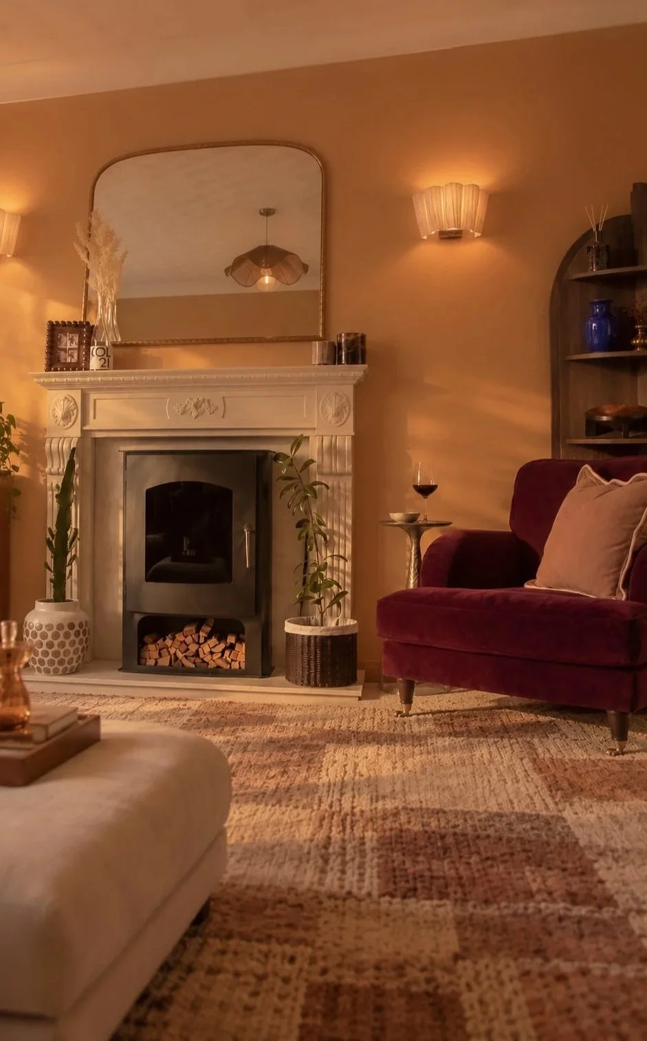 Living room interior design in Nantwich, Cheshire, with a burgundy armchair, fireplace and warm layered lighting