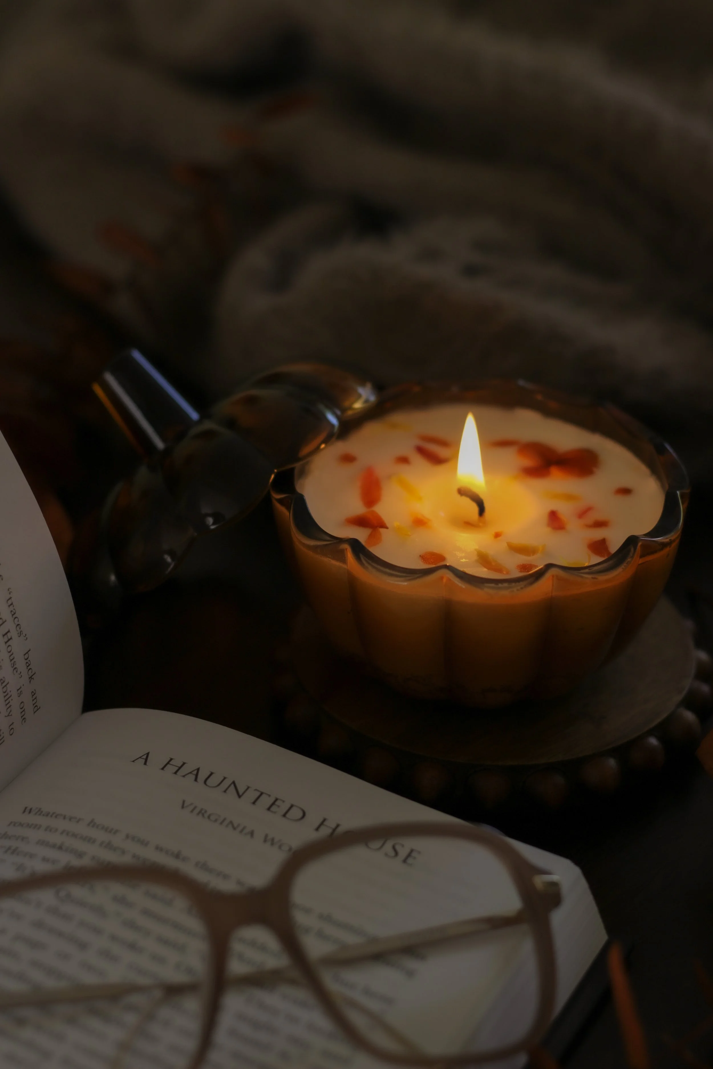 Lifestyle product photography for Moon Sister Candles, featuring a lit candle styled with a book and glasses