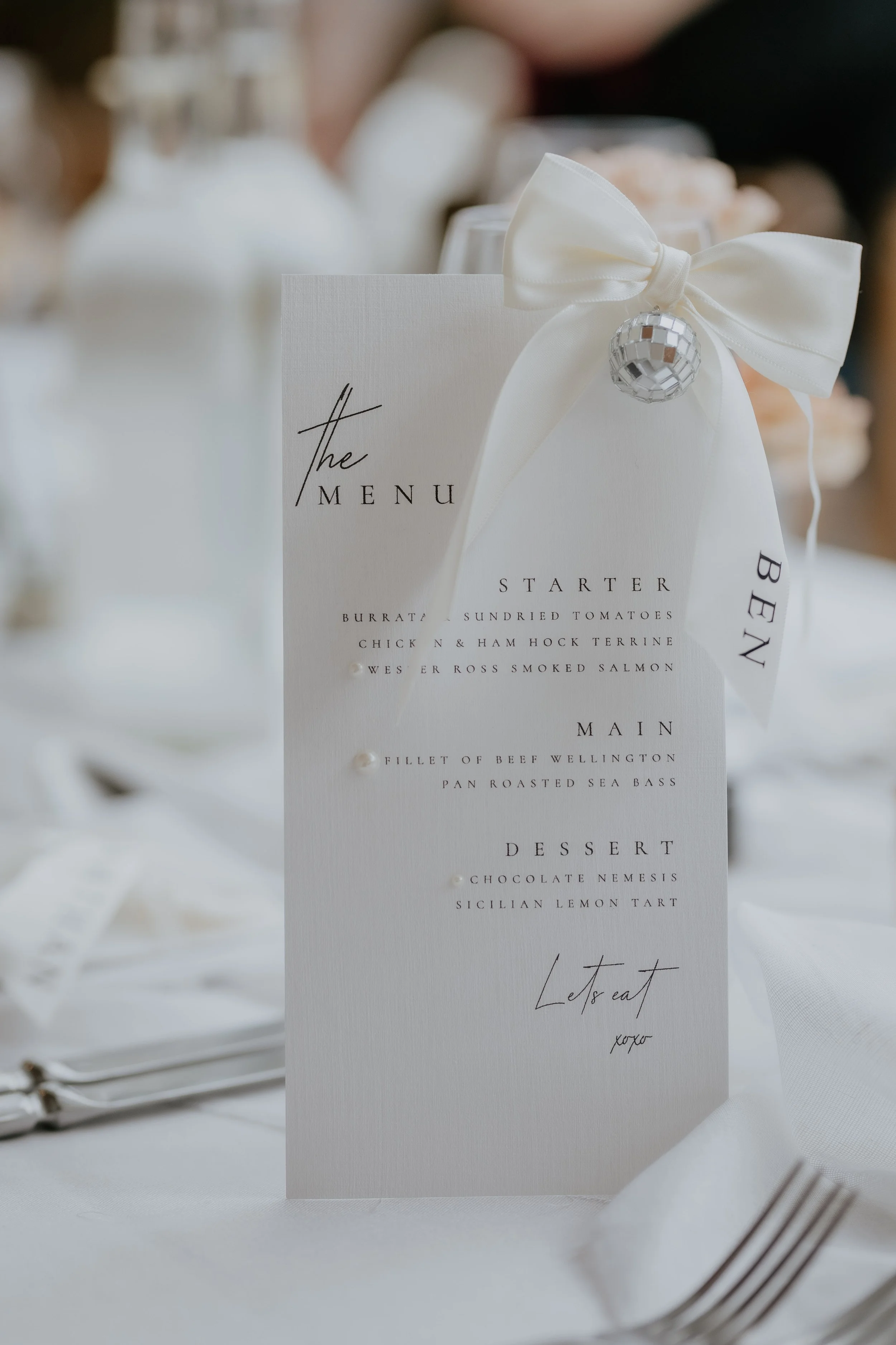 Wedding table styling at Hampton Court featuring a bespoke menu, satin bow and disco ball detail
