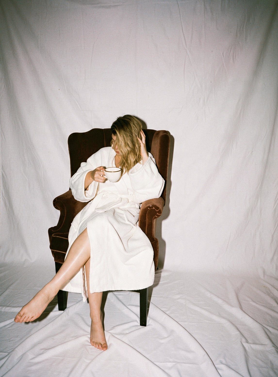 Lifestyle portrait of Tasmin Casey, founder of Sunday House, relaxing in an armchair with a mug