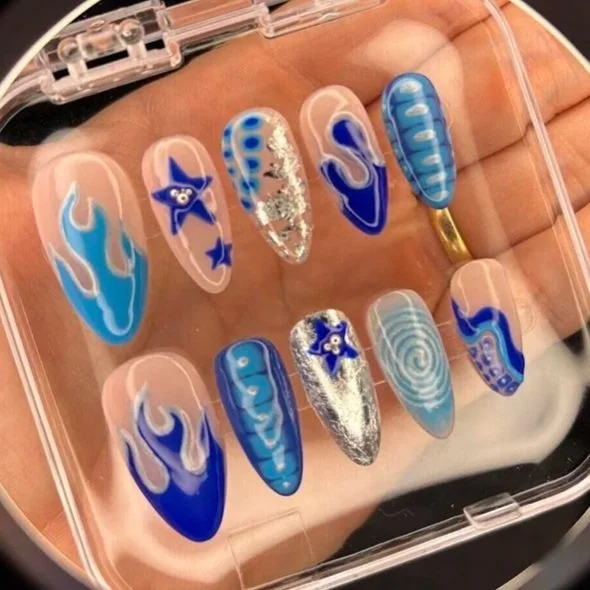 Set of twelve decorated false nails with blue and white flame, starfish, and swirl designs, stored in a clear plastic case.