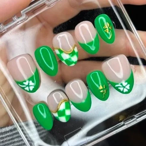 Nail art with green and white designs, including some with shamrock and four-leaf clover patterns.