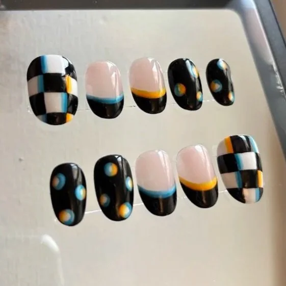 Set of artificial nails with a geometric black, white, light blue, and yellow design.